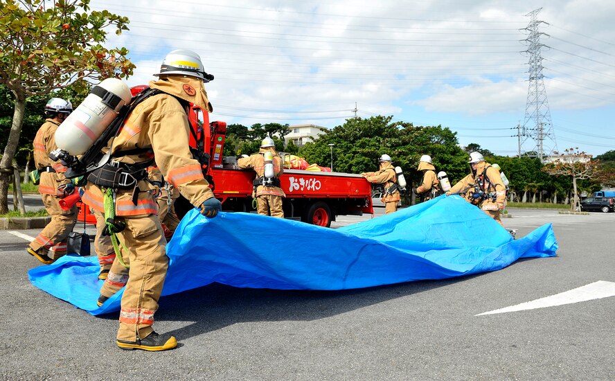 Members of Okinawa City Fire Department prepare an evaluation area during a bilateral hazardous materials training exercise, Dec. 8, 2015, at the Okinawa City Civic Center, Japan. A total of 15 firefighters from the Okinawa City Fire Department and four members from the Kadena Air Base Fire Department participated in a bilateral hazardous materials training exercise to further develop the cooperation and teamwork necessary to combat any type of hazardous materials threat with their local counterparts. (U.S. Air Force photo by Naoto Anazawa)