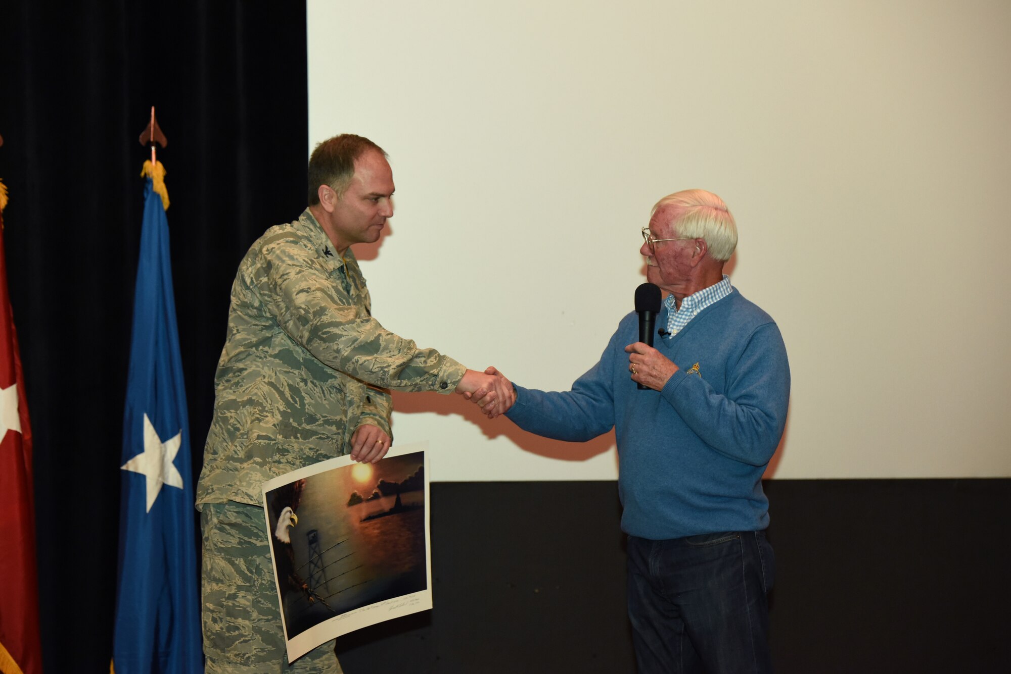 Retired U. S. Air Force Col. Ed Hubbard presents a limited edition lithograph that he painted in the early 1980s to 153rd Airlift Wing Commander Col. Bradley Swanson. Hubbard detailed his experiences as a POW and provided insight on keeping a positive attitude during captivity. (U.S. Air National Guard photo by Tech. Sgt. John Galvin/released)