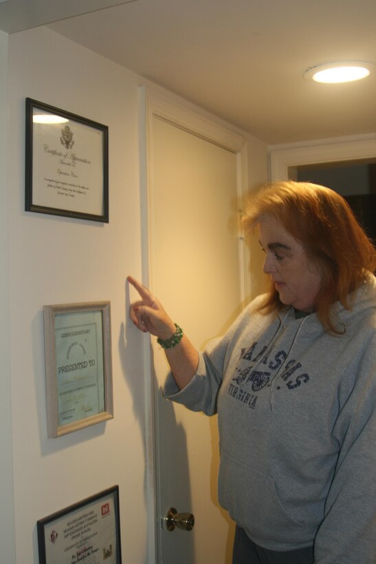 Joyce Ammen, founder and total staff of Operation Care, a nonprofit that provides food and non-perishable items to servicemen and military families, stands in her Lorton, Virginia, townhouse with framed thank-you letters from units she's worked with.