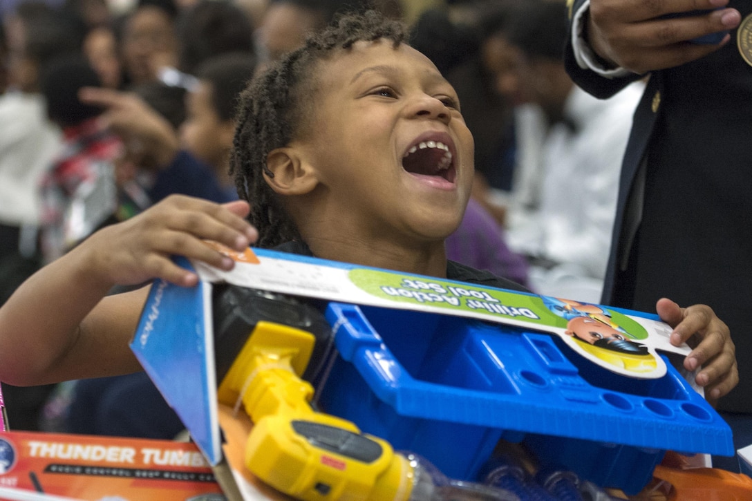 A child smiles after finding a box full of toys during a Toys for Tots event on Joint Base Anacosta-Bolling in Washington, D.C., Dec. 9, 2015. DoD photo by EJ Hersom