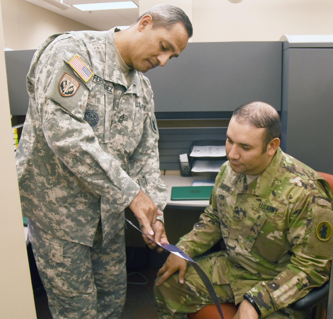 Former drill sergeant Master Sgt. Tomas Fernandez (left), human resources plans and operation noncommissioned officer with U.S. Army South, explains how to prepare an award certificate to Sgt. Jamie Garcia, a personnel management NCO, as part of a one-on-one training session. Fernandez served as a drill sergeant from 2005-2007 at Fort Jackson, S.C.  