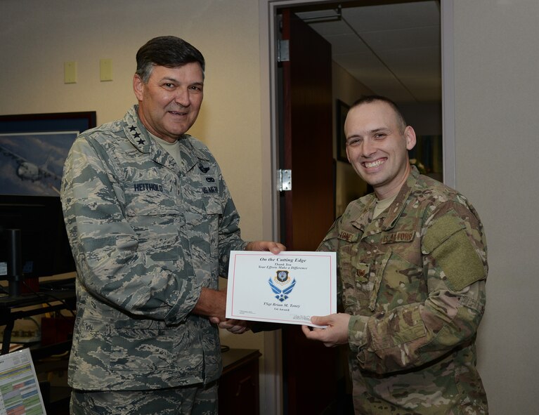 Lt. Gen. Brad Heithold, commander of Air Force Special Operations Command, presents a Cutting Edge award to Tech. Sgt. Brian Toney, HQ AFSOC NCO in charge of executive communications, at Hurlburt Field, Fla., Dec. 9, 2015. (U.S. Air Force photo/Staff Sgt. Melanie Holochwost)