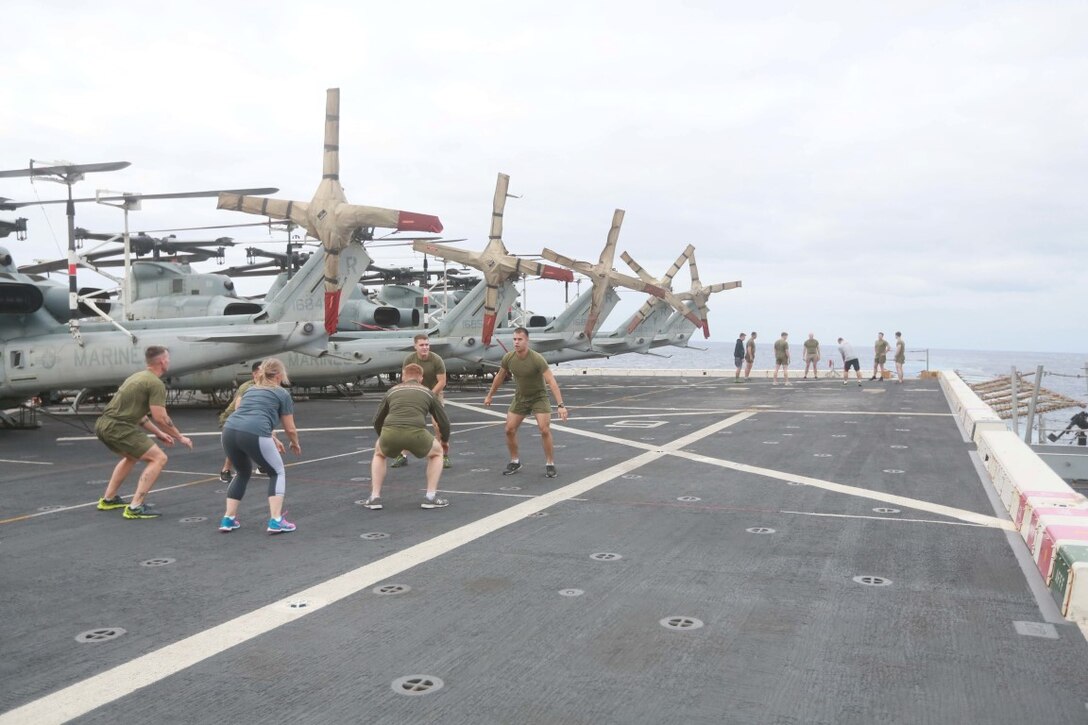 PACIFIC OCEAN (Dec. 7, 2015) U.S. Marines with 1st Light Armored Reconnaissance Detachment, Battalion Landing Team 3rd Battalion, 1st Marine Regiment, 15th Marine Expeditionary Unit, work out with family members on the flight deck aboard the USS Anchorage (LPD 23). The 15th MEU is coming to the end of deployment and hosting a Tiger Cruise for family members to showcase life aboard the Anchorage. (U.S. Marine Corps photo by Sgt. Steve H. Lopez/Released)