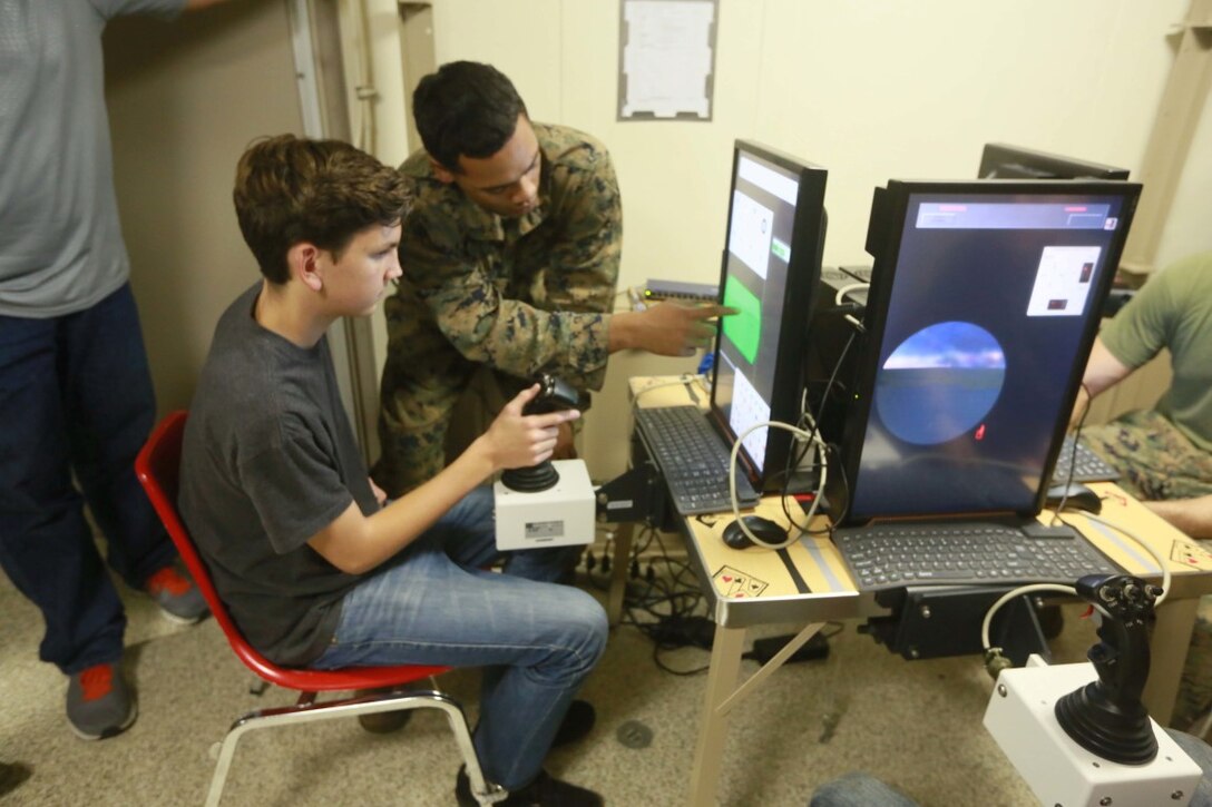 PACIFIC OCEAN (Dec. 7, 2015) U.S. Marines with 1st Light Armored Reconnaissance Detachment, Battalion Landing Team 3rd Battalion, 1st Marine Regiment, 15th Marine Expeditionary Unit, demonstrate to family members how to operate the Light Armored Vehicle simulator aboard the USS Anchorage (LPD 23). The 15th MEU is coming to the end of deployment and hosting a Tiger Cruise for family members to showcase life aboard the Anchorage. (U.S. Marine Corps photo by Sgt. Steve H. Lopez/Released)