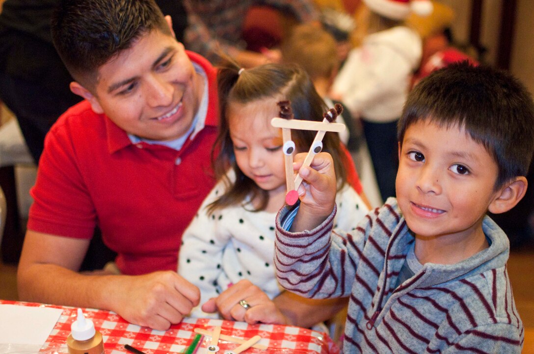 Staff Sgt. Guillermo Garcia, Marine Corps Network Operations and Security Center incident management chief, his spouse Sofia and two children share a holiday meal Dec. 4 at the Lincoln Military Housing clubhouse during the Marine Corps Community Service Exceptional Family Member Program’s annual Christmas party Dec. 4.