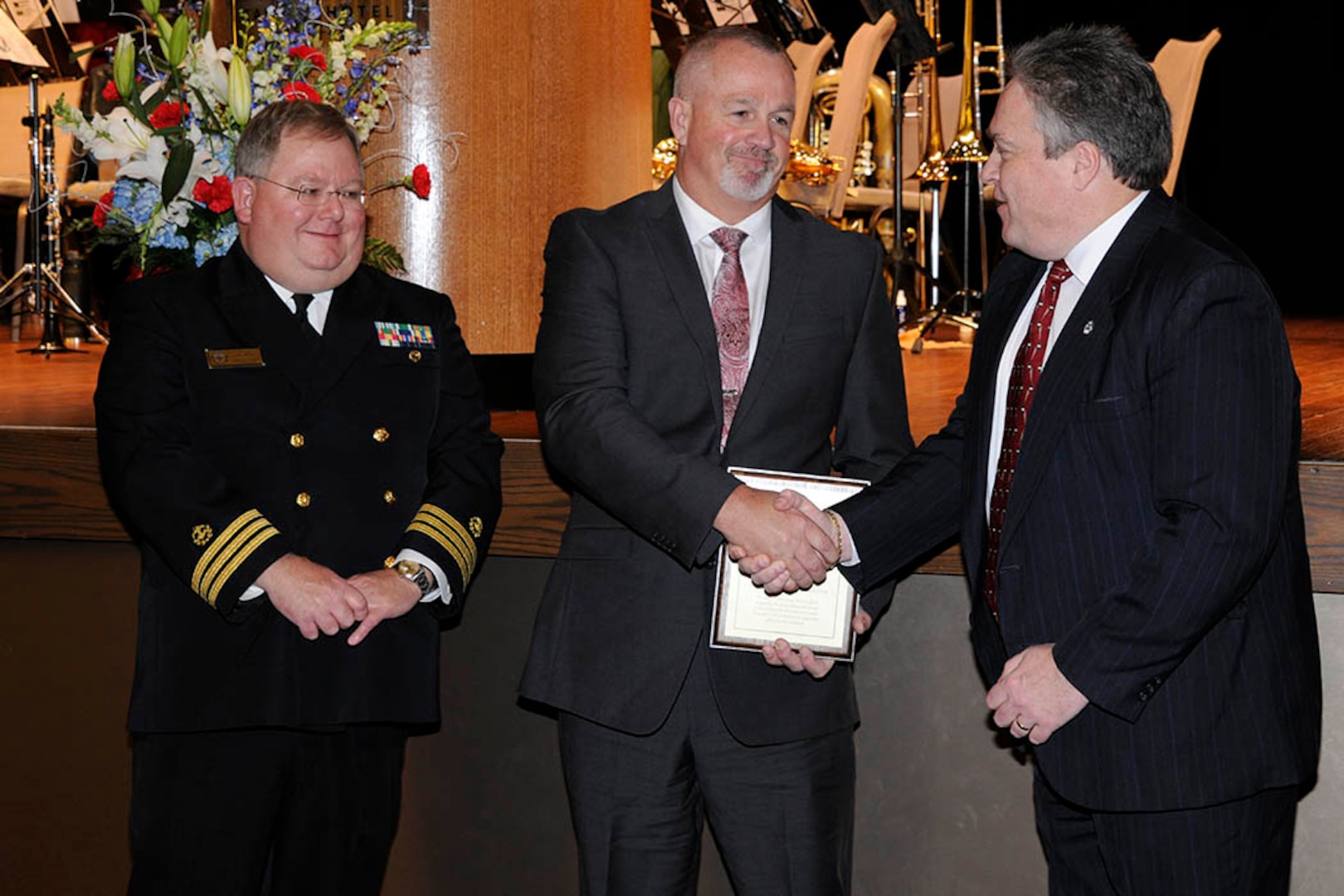 Michael Chapman (center) receives the Hart-Dole-Inouye Federal Center Service Award from Logistics Information Services Director Ray Zingaretti (right) and Retired Navy Cmdr. T.R. Shaw for demonstrating the “spirit of service” synonymous with the center and its namesakes. 