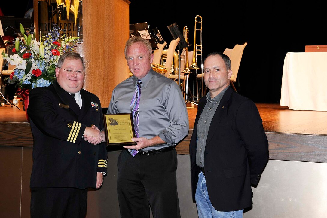 William Cohoe (center) receives the Hart-Dole-Inouye Federal Center Service Award from Don Phillips, acting site manager for DLA Installation Support at Battle Creek (right) and Retired Navy Cmdr. T.R. Shaw for demonstrating the “spirit of service” synonymous with the center and its namesakes. 