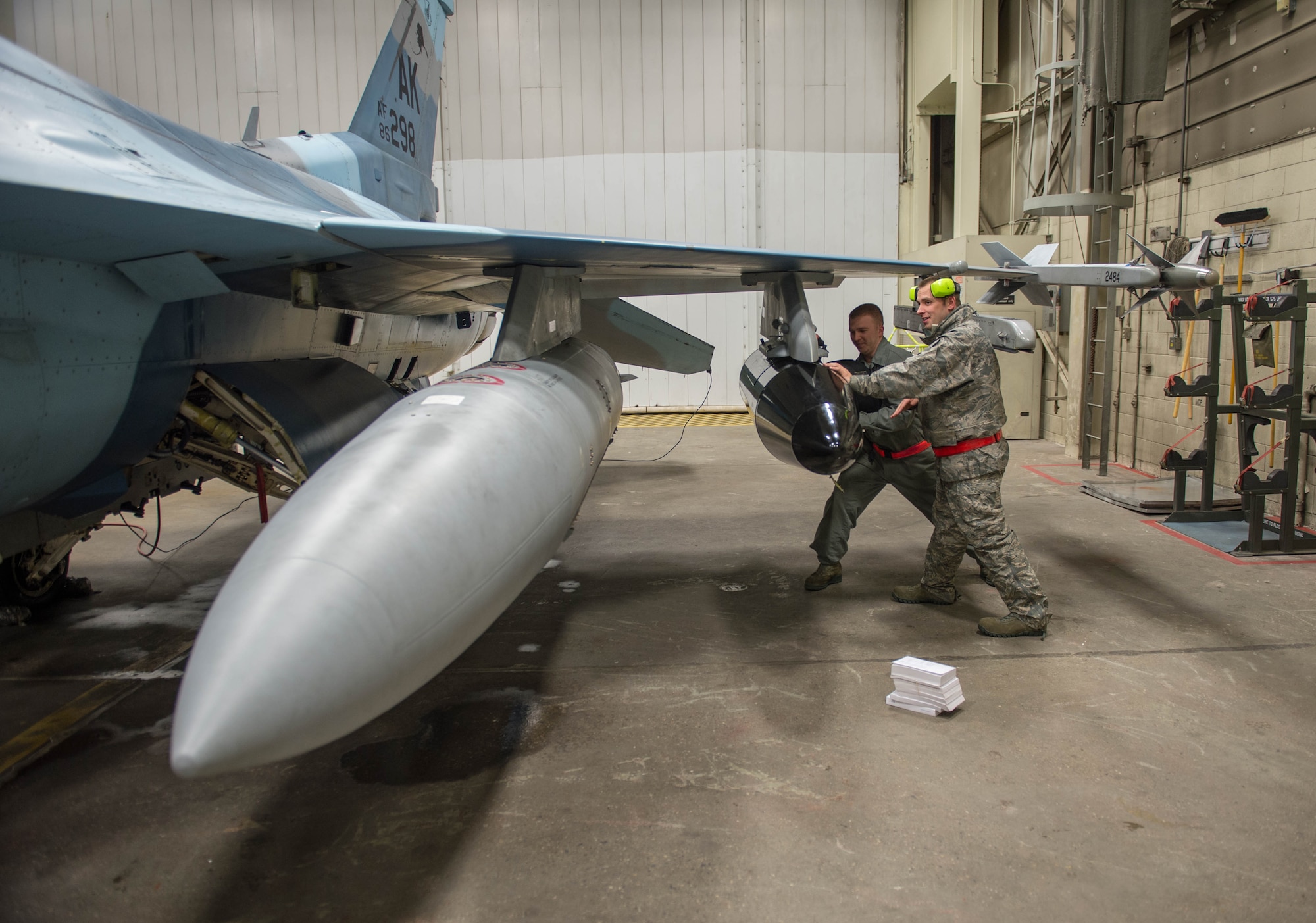 Staff Sgt. Robert Knickle (left) and Timothy Smith, from the 354th Aircraft Maintenance Squadron, push luggage into a pod on an F-16 Fighting Falcon fighter aircraft Dec. 7, 2015, at Eielson Air Force Base, Alaska. More than 30 maintenance Airmen worked an early shift to help launch several jets to Tyndall Air Force Base, Florida, for CHECKERED FLAG 16-1, a large-force exercise that simulates a large number of aircraft in a deployed environment to cross-check weapons systems. (U.S. Air Force photo by Staff Sgt. Shawn Nickel/Released)