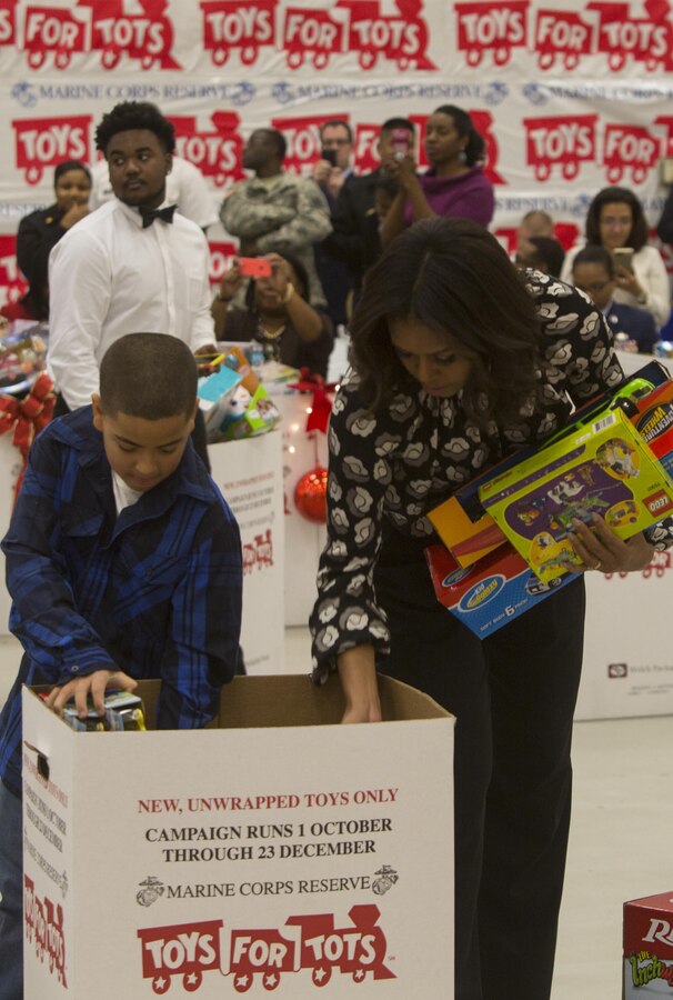 First lady Michelle Obama places a toy in a sorting bin alongside a volunteer at a Toys for Tots event at Joint Base Anacostia-Bolling. The Toys for Tots program was created in 1947 by the Marine Corps Reserve and provides new, unwrapped toys to millions of less fortunate children in communities across the country every year. The first lady is an avid supporter of the program and has been a spokesperson for its mission for the last seven years.  (U.S. Marine Corps photo by Cpl. Ian Leones/Released)