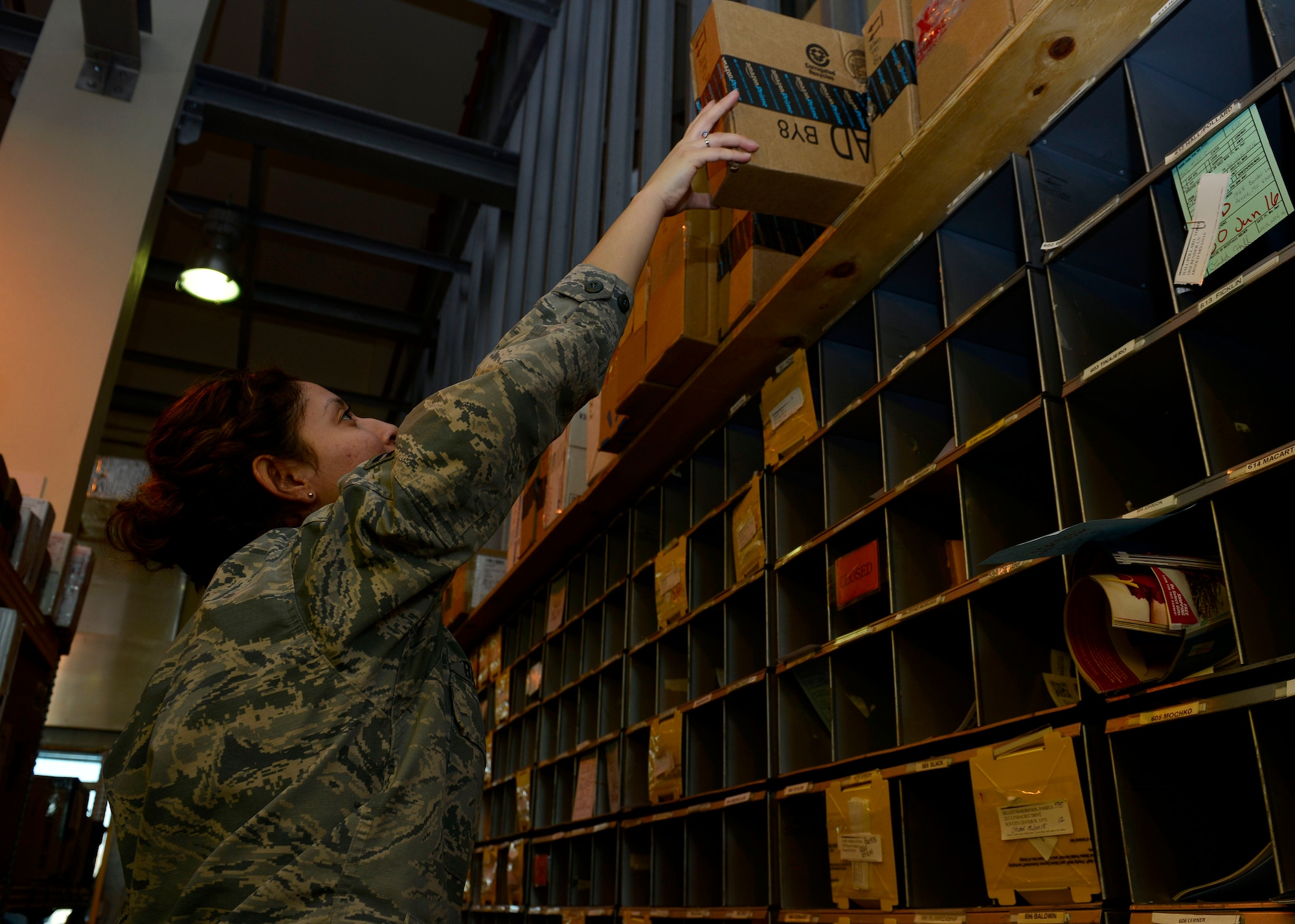 U.S. Air Force Airman 1st Class Marleny Barboza, 31st Communications Squadron postal clerk, grabs a package for a customer, Dec. 9, 2015, at Aviano Air Base, Italy. The post office is always looking for volunteers to help postal clerks unload trucks, sort mail, pitch letters into mailboxes and assist customers at the service window. (U.S. Air Force photo by Airmen 1st Class Cary Smith/Released)