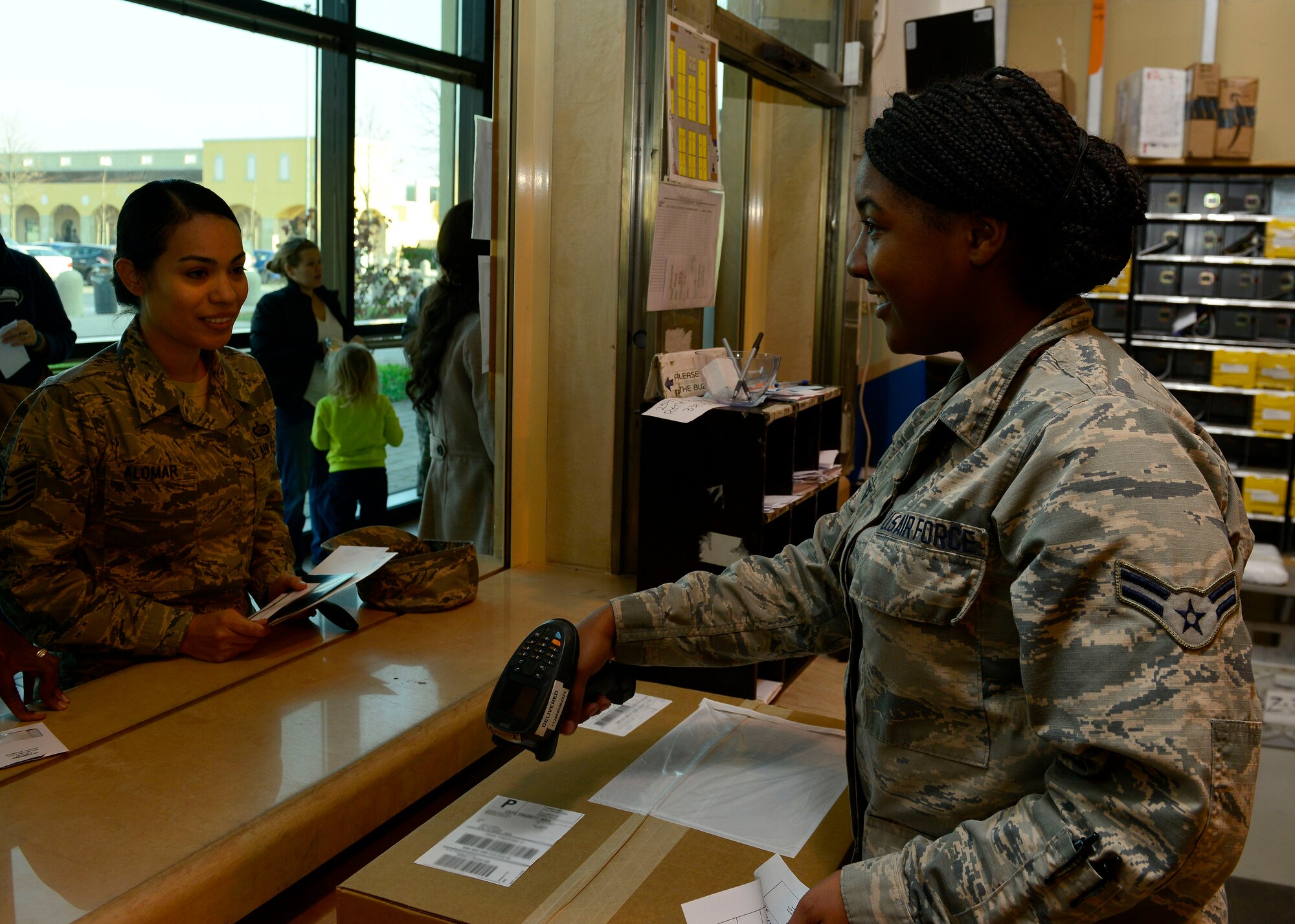 (From right) U.S. Air Force Airman 1st Class Alexis George, 31st Communications Squadron postal clerk, scans a package for Tech. Sgt. Pearl Alomar, 31st Logistics Readiness Squadron command support section NCO in charge, Dec. 9, 2015, at Aviano Air Base, Italy. The post office receives an average 1,500 to 2,000 packages daily during the holiday season. (U.S. Air Force photo by Airmen 1st Class Cary Smith/Released)