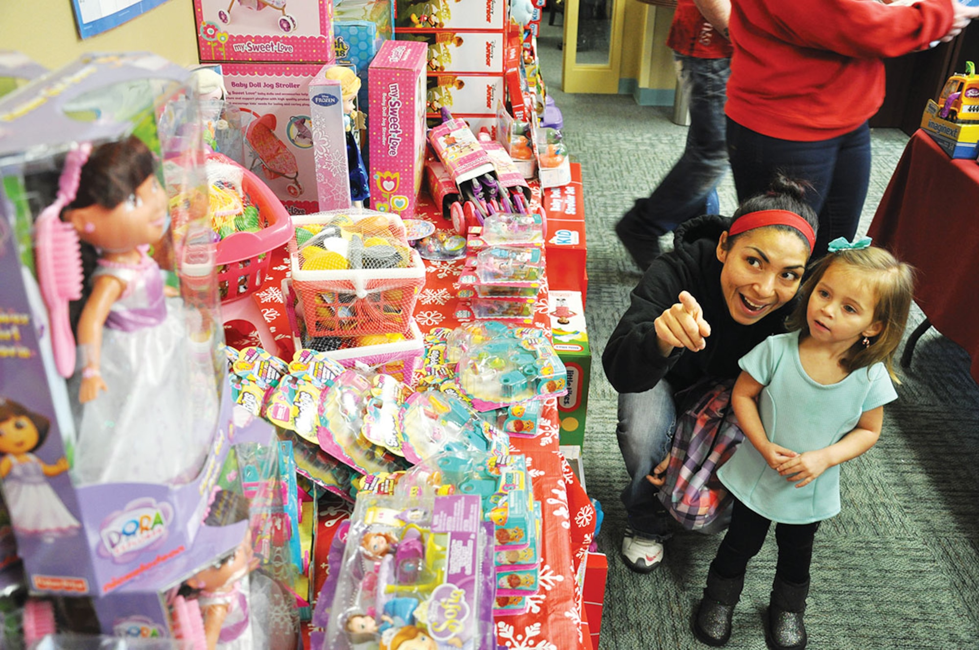 Gloria Schiers, wife of Staff Sgt. Nathan Schiers, 962d Airborne Air Control Squadron communications systems operator, points out a doll to her daughter Kambryn, 3, at the third annual Operation Homefront holiday toy distribution event at Joint Base Elmendorf-Richardson Dec. 4. (U.S. Air Force photo/Staff Sgt. Wes Wright)