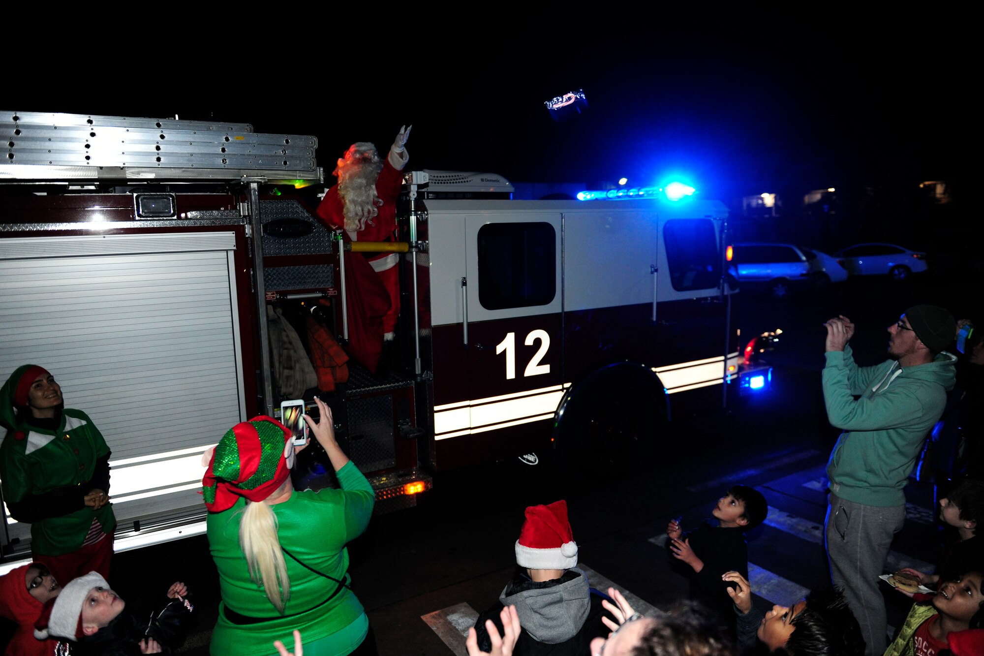Members of ‘Team Incirlik’ take pictures of Santa Claus as he arrives by fire truck during the 2015 Incirlik Holiday Tree Lighting ceremony Dec. 1, 2015, at Incirlik Air Base, Turkey. After Santa Claus finished handing out candy, families had an opportunity to take photos with him.   (U.S. Air Force photos by Senior Airman Krystal Ardrey/Released)