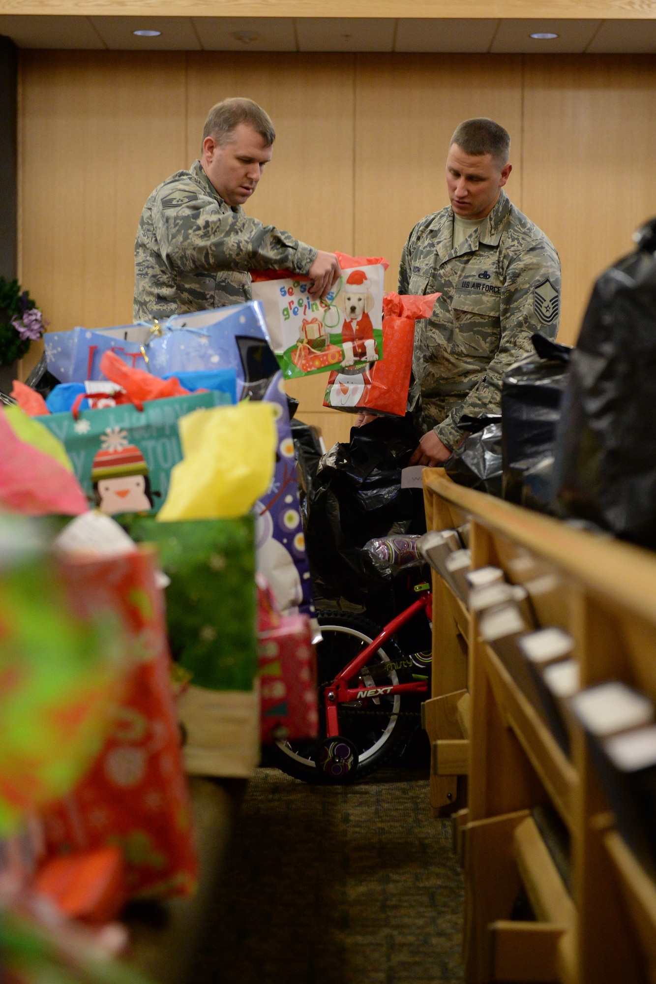 Master Sgt. Wayne Hulse places Angel Tree gifts into a bag held by Master Sgt. Jason Koth Dec. 9 in the chapel at Hill Air Force Base. Volunteers sorted and bagged over 800 gifts this year. (U.S. Air Force photo by R. Nial Bradshaw)