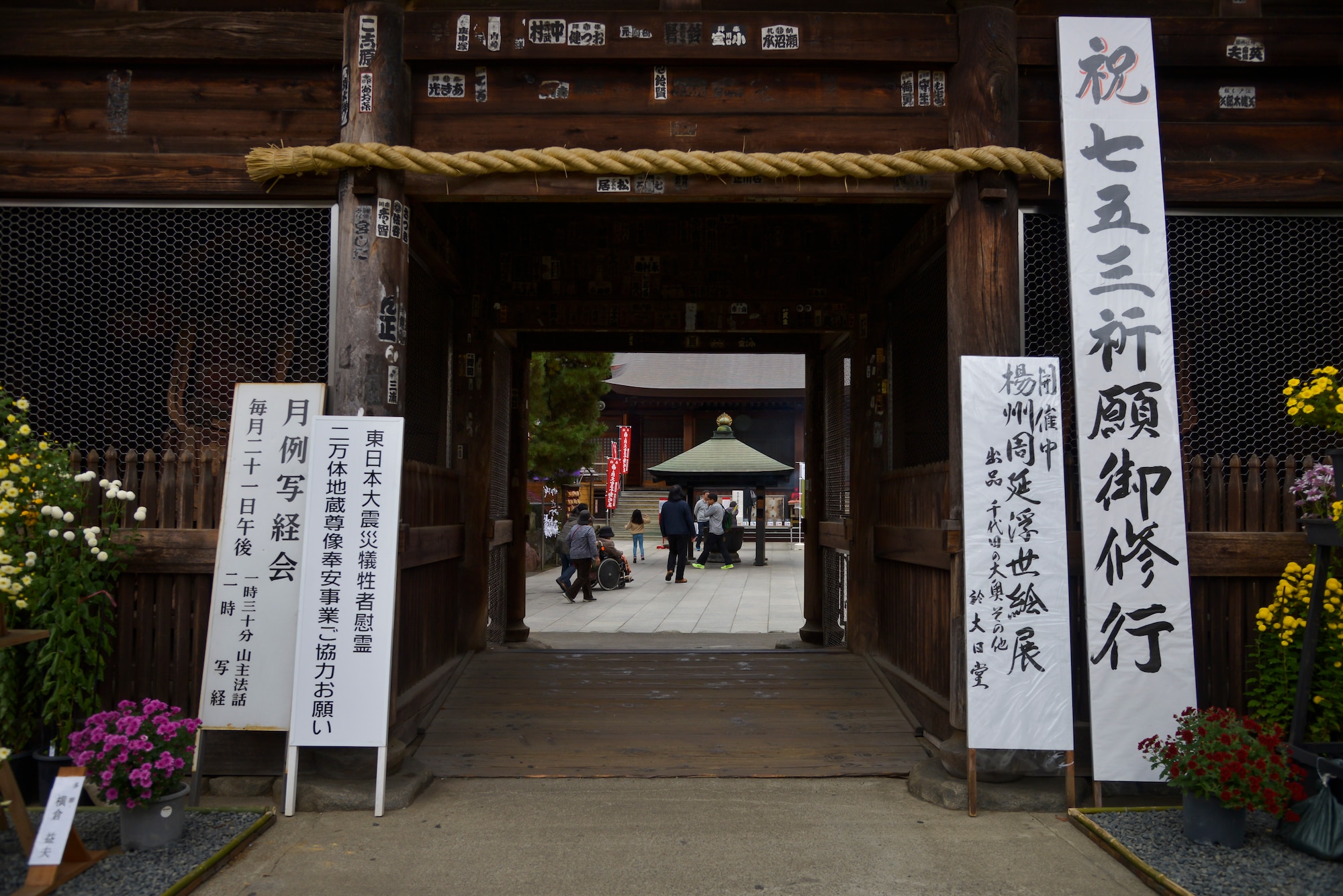 People walk towards a chuzo at the Takahata Fudo Temple grounds in Hino City, Japan, Nov. 1, 2015. Chozu’s are used to purify a person’s hands and mouth before they pray. (U.S. Air Force photo by Senior Airman David Owsianka/Released)