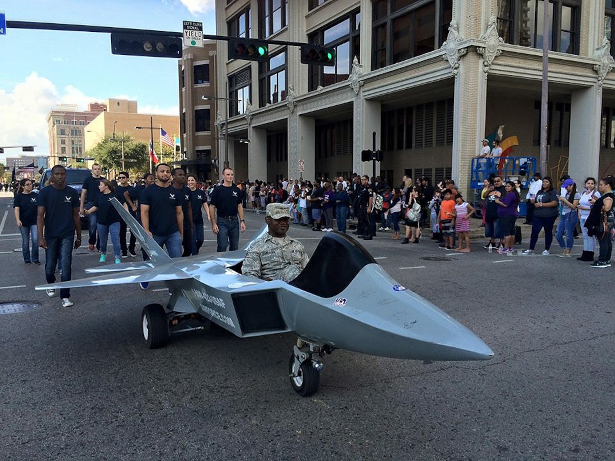 Staff Sgt. Kevin Schroeder drives the F-22 mini jet through downtown Dallas, Nov. 11, 2015. Members of the 344th Recruiting Squadron A-Flight and their Delayed Entry Program participated in the annual Dallas Veterans Day Parade. (U.S. Air Force photo)