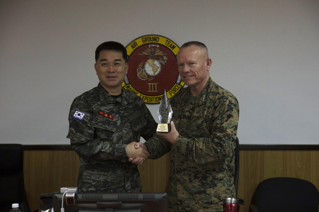 Lt. Gen. Larry Nicholson, the commanding general of III Marine Expeditionary Force, right, presents Lt. Gen. Sang Hoon Lee, commandant of the of the Republic of Korea Marine Corps, left, with a gift Dec. 11, at III MEF Headquarters, Camp Courtney. Lee was on Okinawa from Dec. 11 to increase awareness of senior leader collaboration and oneness as the Combined Marine Component Command. The CMCC is a focused combined force designed to protect the safety and security of the people of Korea. (U.S. Marine Corps photo by Cpl. Abbey Perria/Released)