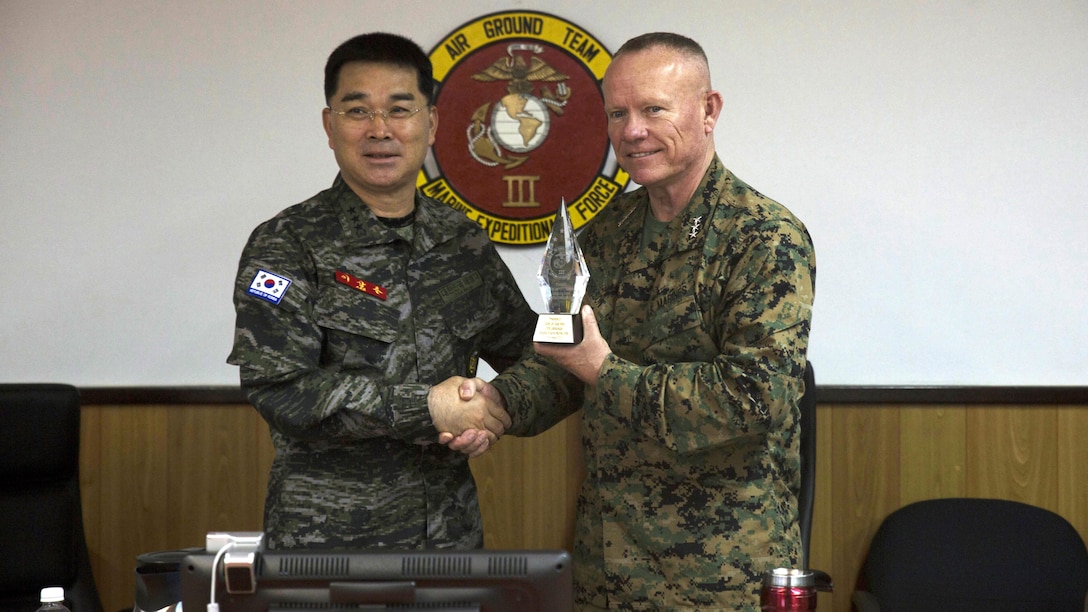 Lt. Gen. Larry Nicholson, the commanding general of III Marine Expeditionary Force, right, presents Lt. Gen. Sang Hoon Lee, commandant of the of the Republic of Korea Marine Corps, left, with a gift Dec. 11, 2015 at III MEF Headquarters, Camp Courtney, Okinawa, Japan. Lee was on Okinawa from Dec. 11 to increase awareness of senior leader collaboration and oneness as the Combined Marine Component Command. The CMCC is a focused combined force designed to protect the safety and security of the people of Korea.