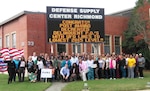 Defense Logistics Agency Aviation Supplier Operations Directorates’ Contract Administration team members proudly pose under the flashing marquee at Defense Supply Center Richmond, Virginia. Nov. 11, 2015.