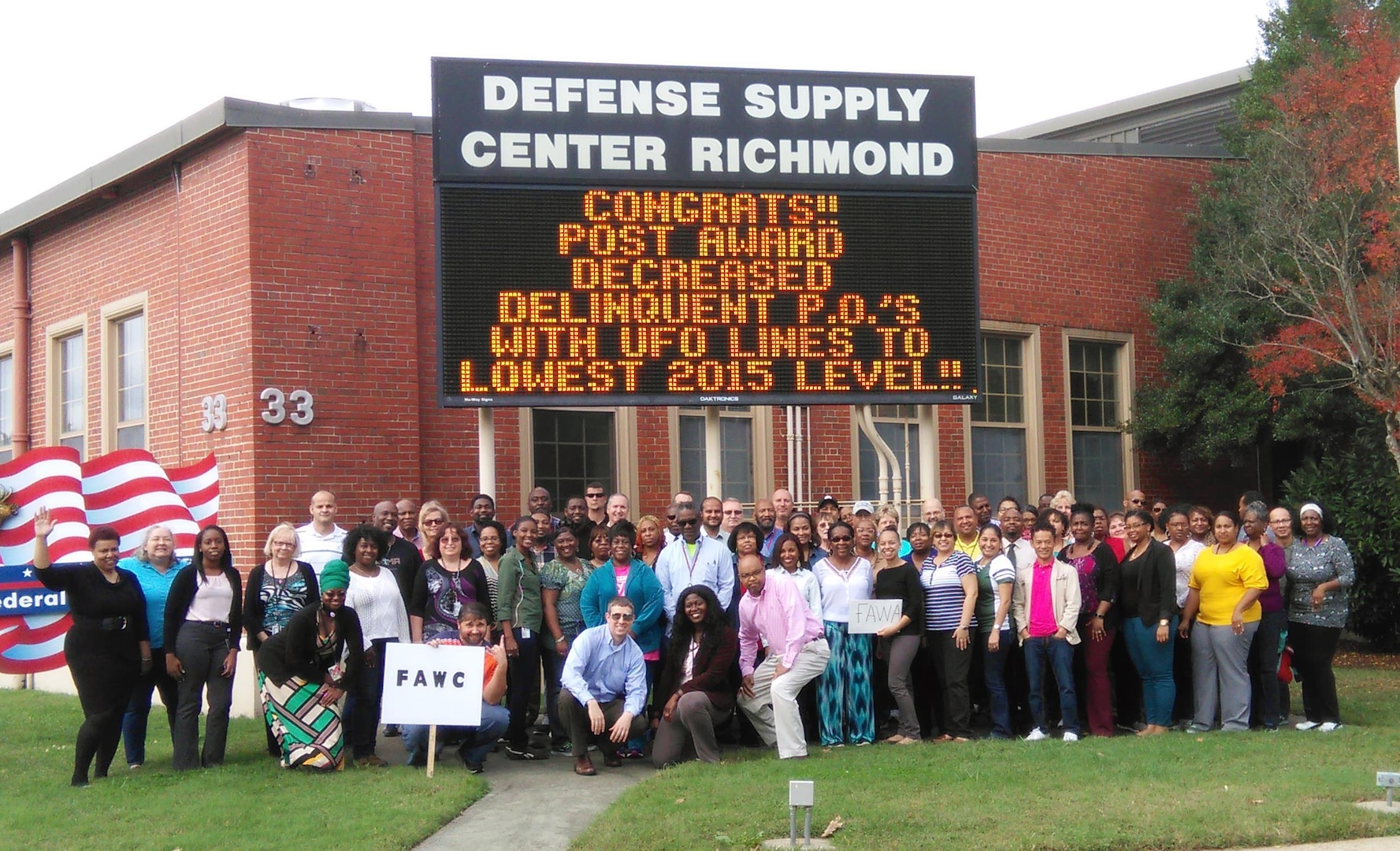 Defense Logistics Agency Aviation Supplier Operations Directorates’ Contract Administration team members proudly pose under the flashing marquee at Defense Supply Center Richmond, Virginia. Nov. 11, 2015.