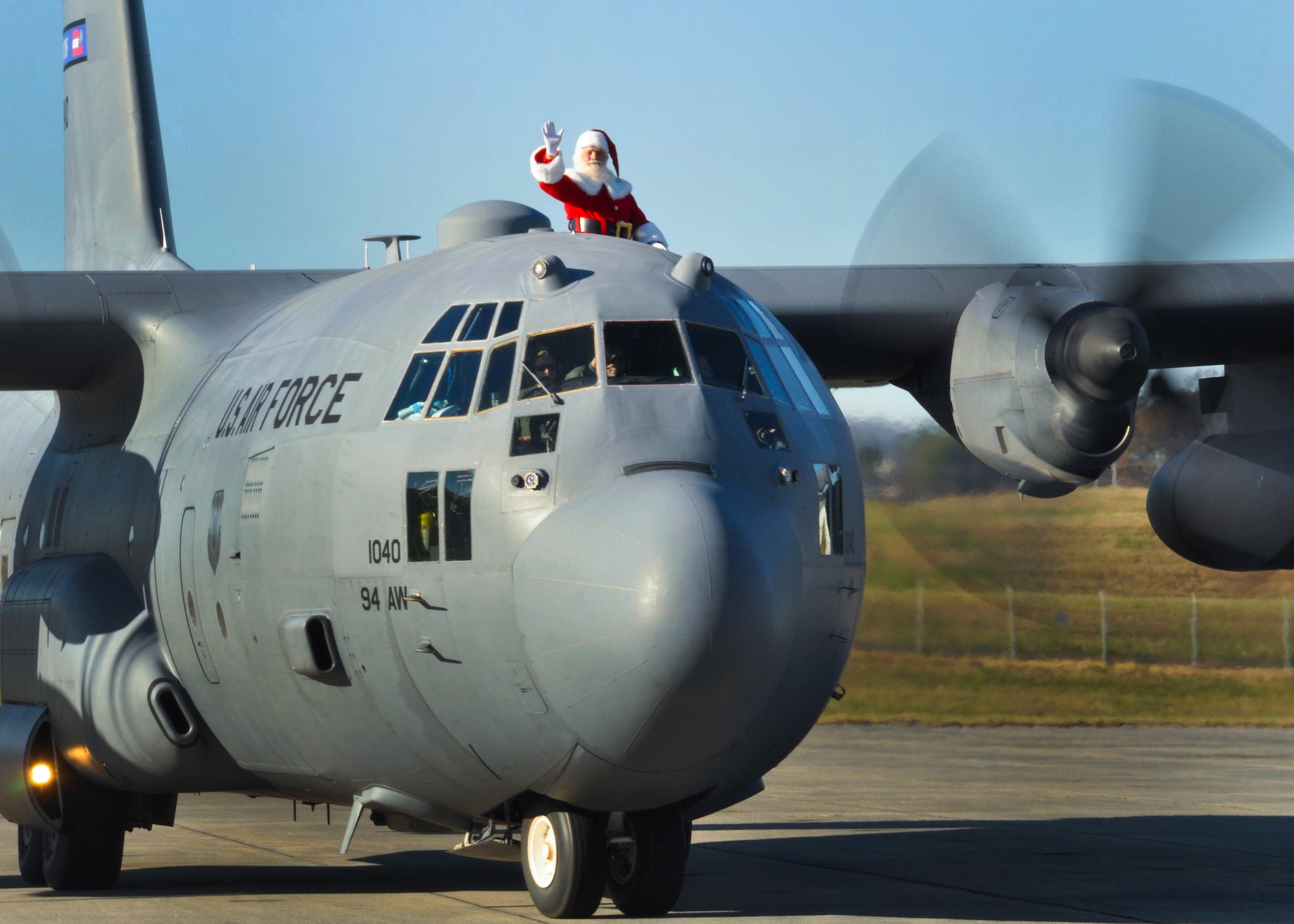 Santa Claus greets a Dobbins family members as he taxis down the flightline to Hangar 5 at Dobbins Air Reserve Base, Ga. on Dec. 5, 2015. Claus took time to shake hands and take pictures with family members waiting for him to arrive via a C-130 Hercules. (U.S. Air Force photo/Senior Airman Miles Wilson)