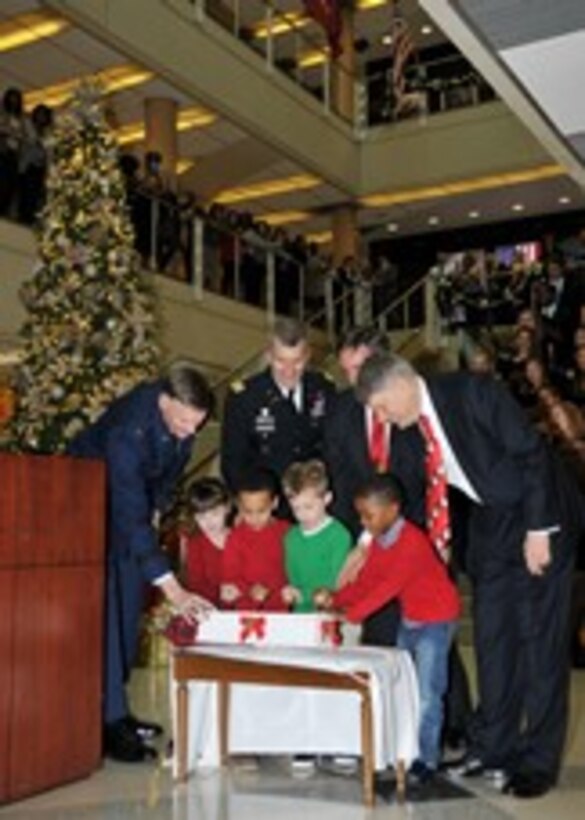McNamara Headquarters Complex senior leaders assist children from the HQC Child Development Center’s kindergarten class as they pull the lever that illuminates the tree at the HQC Tree Lighting and Holiday Social Dec. 9. 