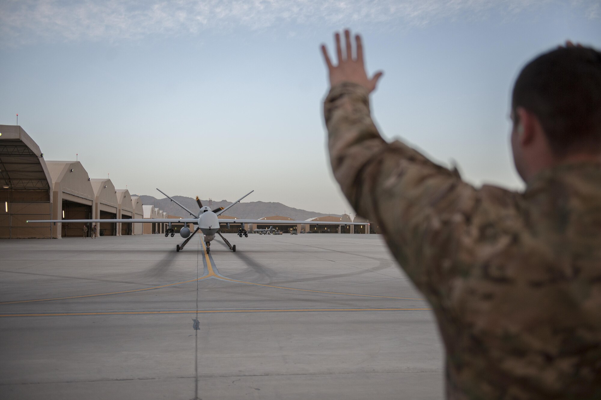 Senior Airman Christopher, 62nd Expeditionary Reconnaissance Squadron weapons load crew member, marshals an MQ-9 Reaper for end-of-runway checks at Kandahar Airfield, Afghanistan, Dec. 6, 2015. The Reaper is an armed, multi-mission, medium-altitude, long-endurance remotely piloted aircraft that is employed primarily as an intelligence-collection asset and secondarily against dynamic execution targets. (U.S. Air Force photo by Tech. Sgt. Robert Cloys/Released)