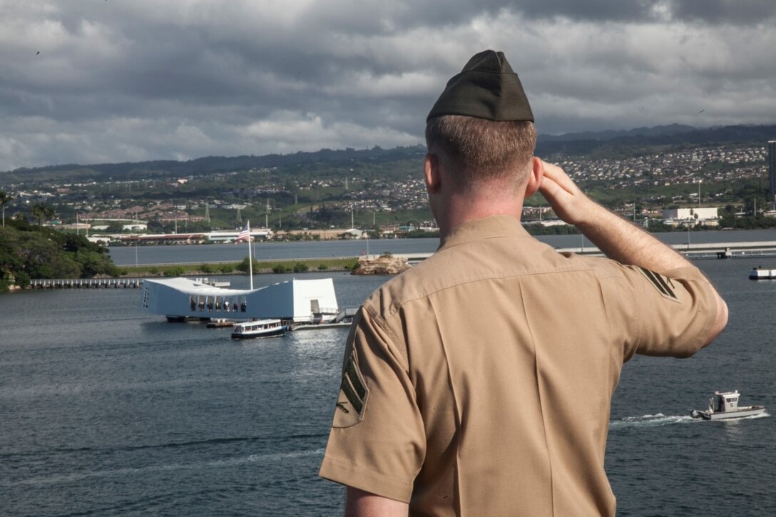 PEARL HARBOR, Hawaii (Dec. 3, 2015) A U.S. Marine with the 15th Marine Expeditionary Unit pays respect to the USS Arizona while manning the rails on the flight deck of the USS Essex (LHD-2).  Hawaii is the 15th Marine Expeditionary Unit’s last port call before heading home after their WESTPAC 15 deployment. (U.S. Marine Corps photo by Sgt. Elize McKelvey/Released)