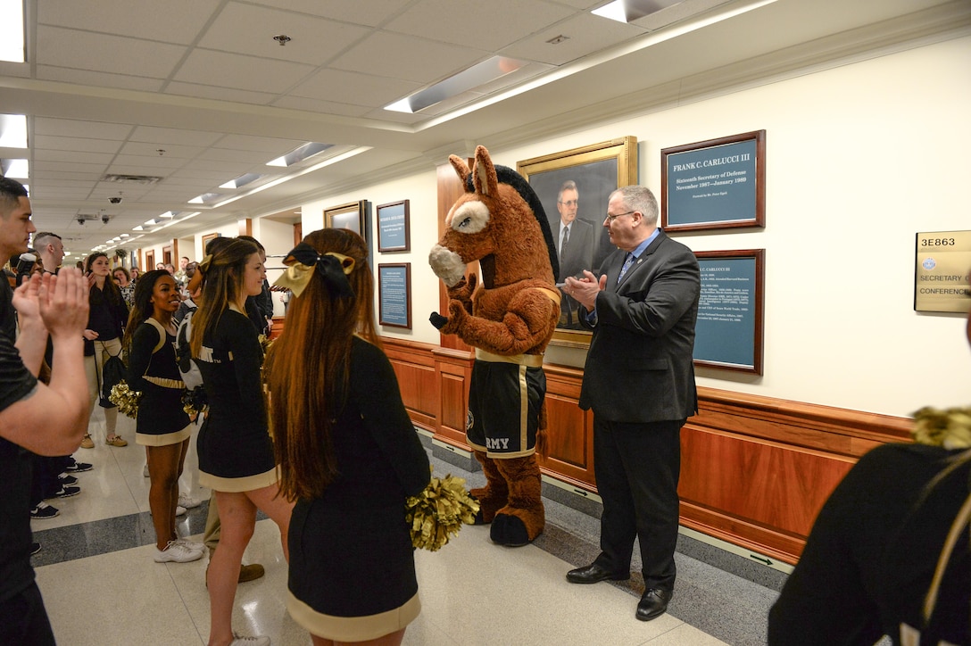 Deputy Defense Secretary Bob Work stands next to the Army's mule mascot and claps as Army cheerleaders perform at the Pentagon, Dec. 11, 2015. DoD photo by Army Sgt. 1st Class Clydell Kinchen