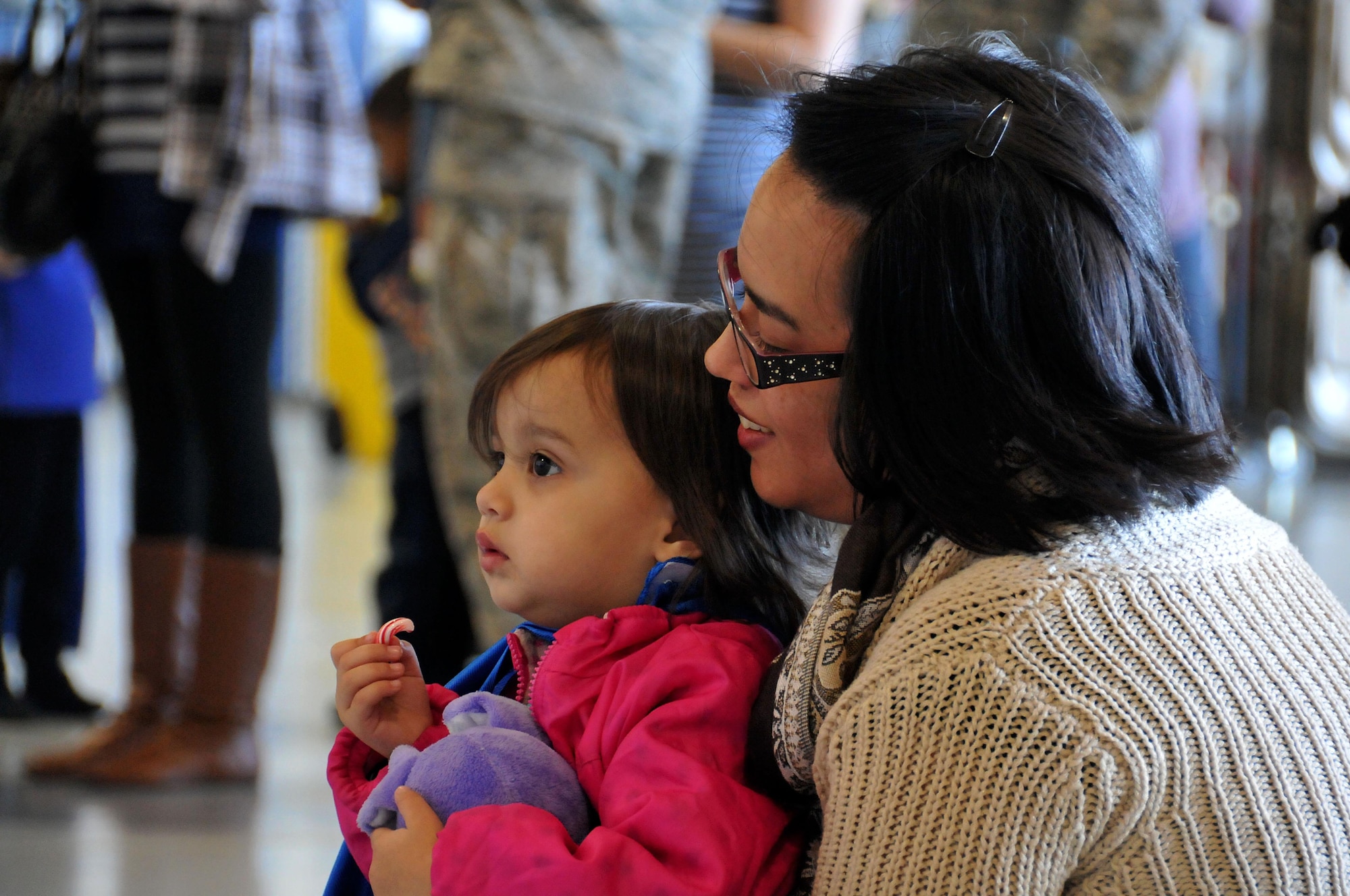 A mother and her daughter look on as Mr. and Mrs. Claus make their way to the stage inside Hangar 5 at Dobbins Air Reserve Base, Ga. on Dec. 5, 2015. The Clauses listened to Christmas wishes of both children and adult alike before handing them goody bags to hold them over until Christmas Day. (U.S. Air Force photo/Senior Airman Andrew Park)