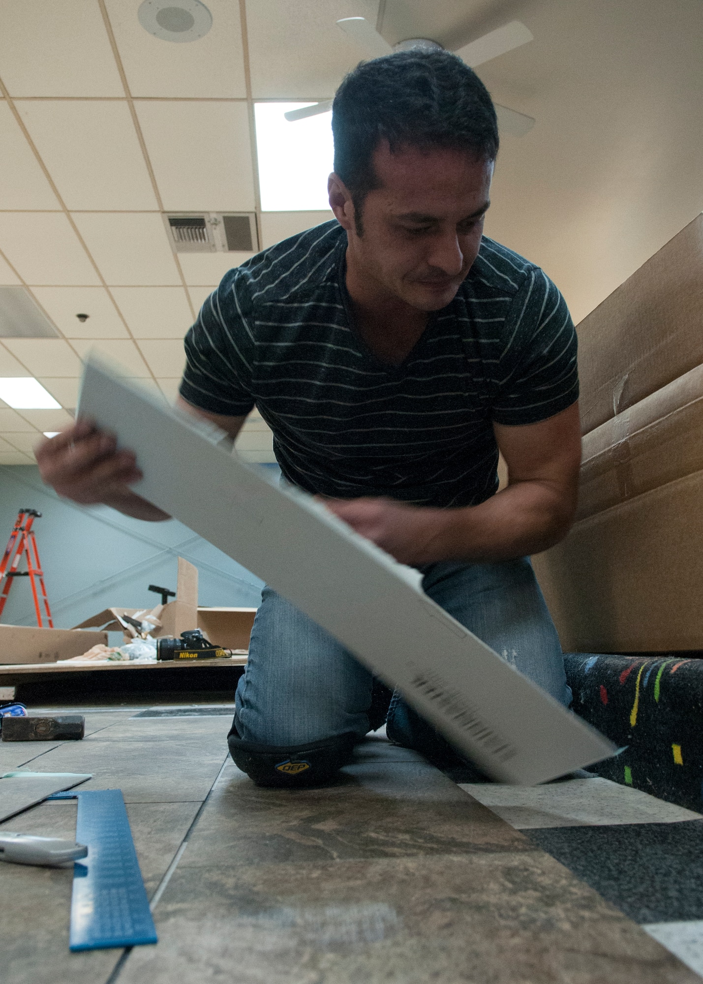 Aaron Ginn, 90th Force Support Squadron member, lays down new tiles in the Warren Bowling Center on F.E. Warren Air Force Base, Wyo., Dec. 9, 2015. The center is slated to re-open Dec. 14, 2015. (U.S. Air Force photo by Airman 1st Class Malcolm Mayfield)