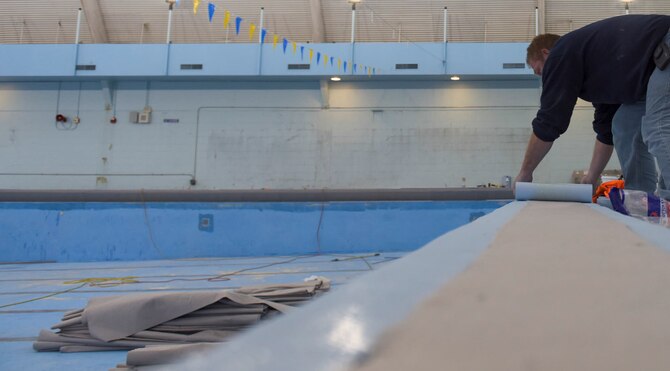 Chuck Mason, project manager for RenoSys construction company out of Indianapolis, Indiana, lays the top portion of the pool liner, Dec. 8, 2015 at Mountain Home Air Force Base, Idaho. The pool will be closed until April for the replacement of the pool liner and the installment of a slick-resistant floor on the pool deck. (U.S. Air Force photo by Senior Airman Jeremy L. Mosier/Released)