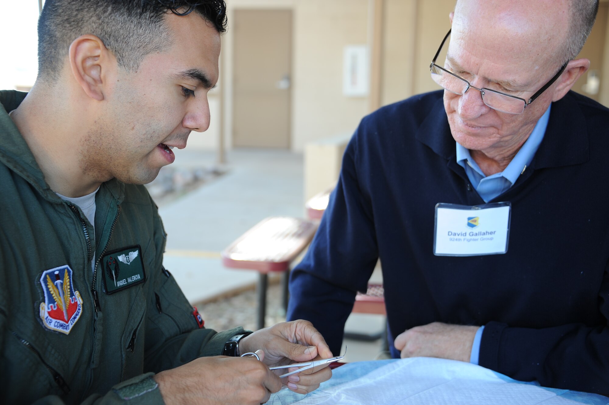 U.S. Air Force Capt. Miguel Valencia, 563rd Operational Support Squadron flight surgeon, shows David Gallaher, 924th Fighter Group honorary commander and managing member and designated broker for Tucson Industrial Realty LLC, how to thread a suture needle at Davis-Monthan Air Force Base, Ariz., Dec. 2, 2015.  D-M AFB’s honorary commanders toured the 355th Medical Group with stops that included the Medical Clinic and the Health and Wellness Center. (U.S. Air Force photo by Airman 1st Class Ashley N. Steffen/Released)