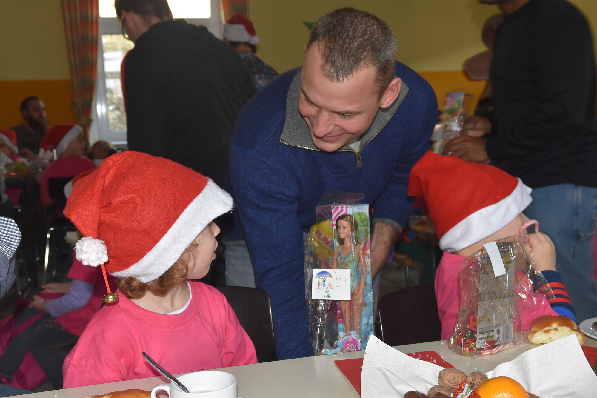 Lt. Col. Christopher Meeker, 52nd Civil Engineer Squadron commander, enjoys a chat with a girl from the Bitburg Saint Martin School while handing out gifts during their annual Sankt Nikolaus celebration Dec. 7. The event was attended by German school officials, teachers and parents, as well as Airmen, spouses and civilians from Spangdahlem Air Base, who helped set up Special Children’s Day at the base earlier in the year. (U.S. Air Force photo by Iris Reiff/Released)