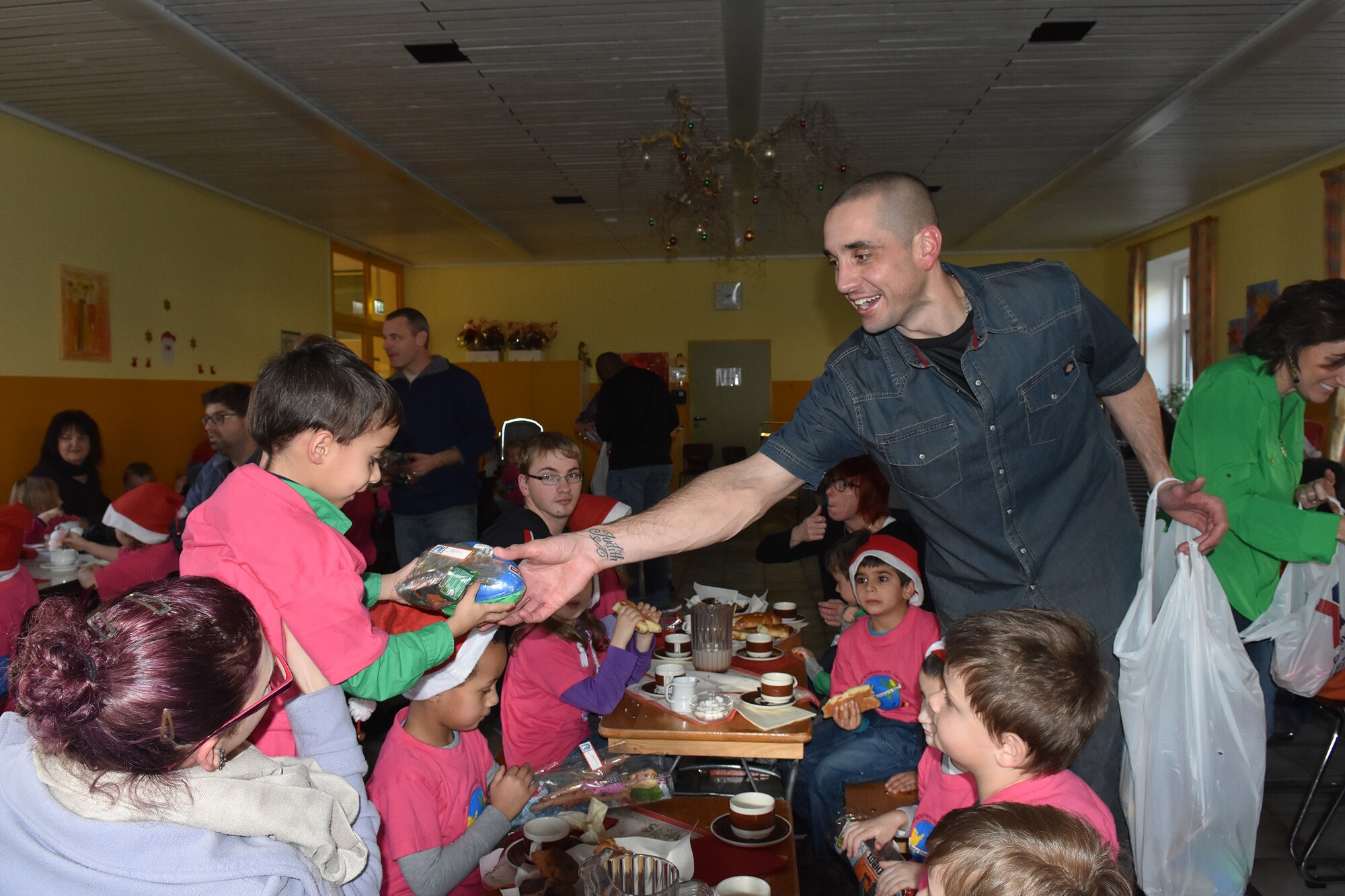 Master Sgt. David C. Dulaney, 52nd Civil Engineer Squadron, hands out a holiday gift to a child at the Bitburg Saint Martin School Dec. 7, during the school’s annual Sankt Nikolaus celebration.  The event was attended by school officials, teachers, parents and a delegation from Spangdahlem Air Base consisting of Airmen, spouses and civilians. Earlier in the summer, the Saint Martin School children visited the base for Special Children’s Day. (U.S. Air Force photo by Iris Reiff/Released)
