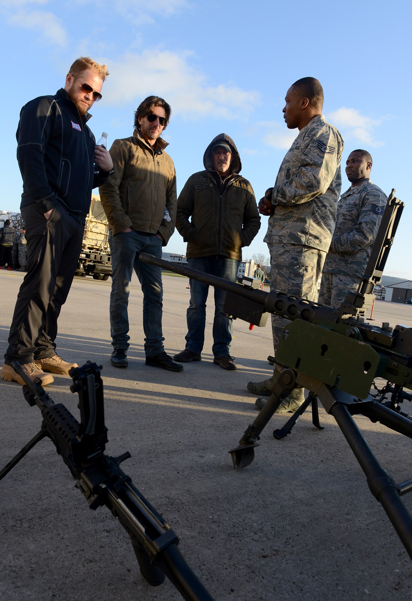 From left, singers and songwriters Kyle Jacobs, Brett James and Billy Montana listen to a brief from Airmen from the 435th Air Ground Operations Wing during the 2015 USO Holiday Troop Tour Dec. 9, 2015, at Ramstein Air Base, Germany. The performers joined other celebrities and the chairman of the Joint Chiefs of Staff to visit service members and their families on the overseas tour. (U.S. Air Force photo/Staff Sgt. Timothy Moore)