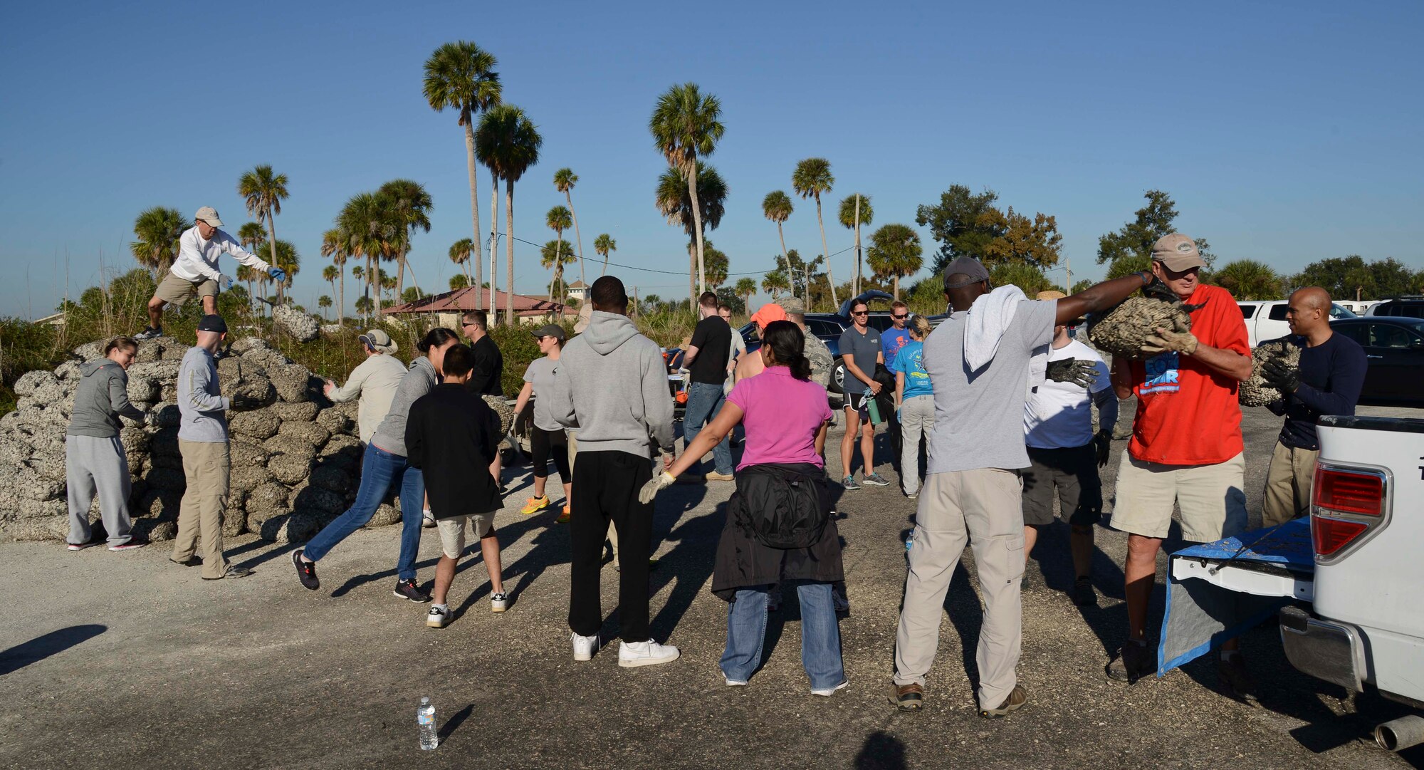 Volunteers form an assembly line and pass bags of shells to be loaded onto a truck at the base Marina on MacDill Air Force Base, Fla., Dec. 11, 2015. Fourteen tons of shells were gathered, bagged, transported and installed to build an oyster reef along the shoreline. (U.S. Air Force photo by Senior Airman Vernon L. Fowler Jr./Released)