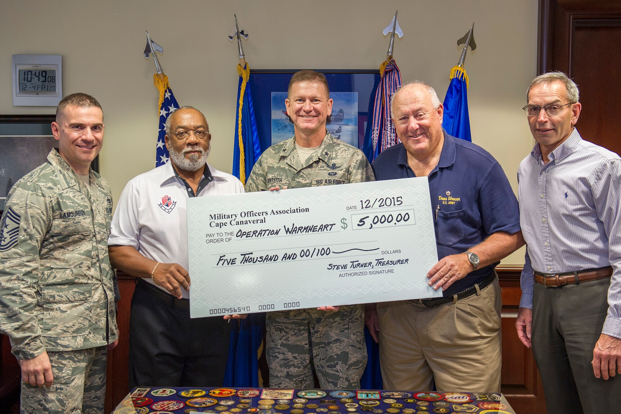 Brig. Gen. Wayne Monteith, 45th Space Wing commander, (center), and Chief Master Sgt. Jason Lamoureux, 45th command chief, (left), accept a $5,000 check on behalf of members of Military Officers Association of America, Cape Canaveral Chapter, in support of Operation Warmheart, Dec. 4, 2015, at Patrick Air Force Base, Fla. Every year around the holidays, MOAA donates money to Operation Warmheart to help military members from all of the different branches assigned to Patrick Air Force Base and Cape Canaveral Air Force Station. The Patrick AFB First Sergeant's Council is responsible for Operation Warmheart and operates solely from donations and money is used to assist Airmen and their families within the wing and its tenant units. (U.S. Air Force photo/Benjamin Thacker) (Released) 