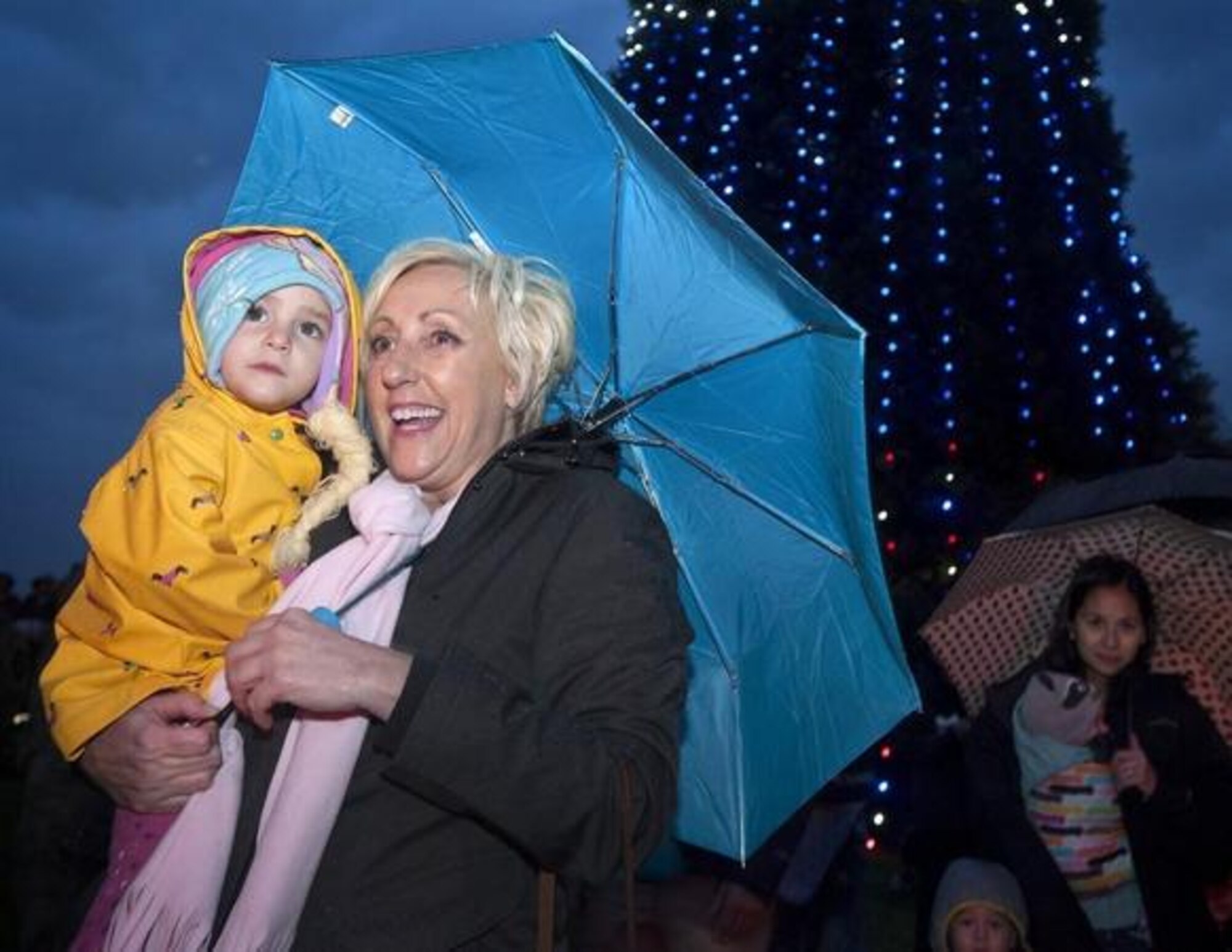 Andrea Dilimone, right, and her granddaughter Angelina Donahue, 2, huddle under an umbrella in the rain Dec. 3 as they await Santa Claus’ arrival during the JBLM Tree Lighting Ceremony on Lewis Main.(Photo by Scott Hansen/Northwest Guardian)