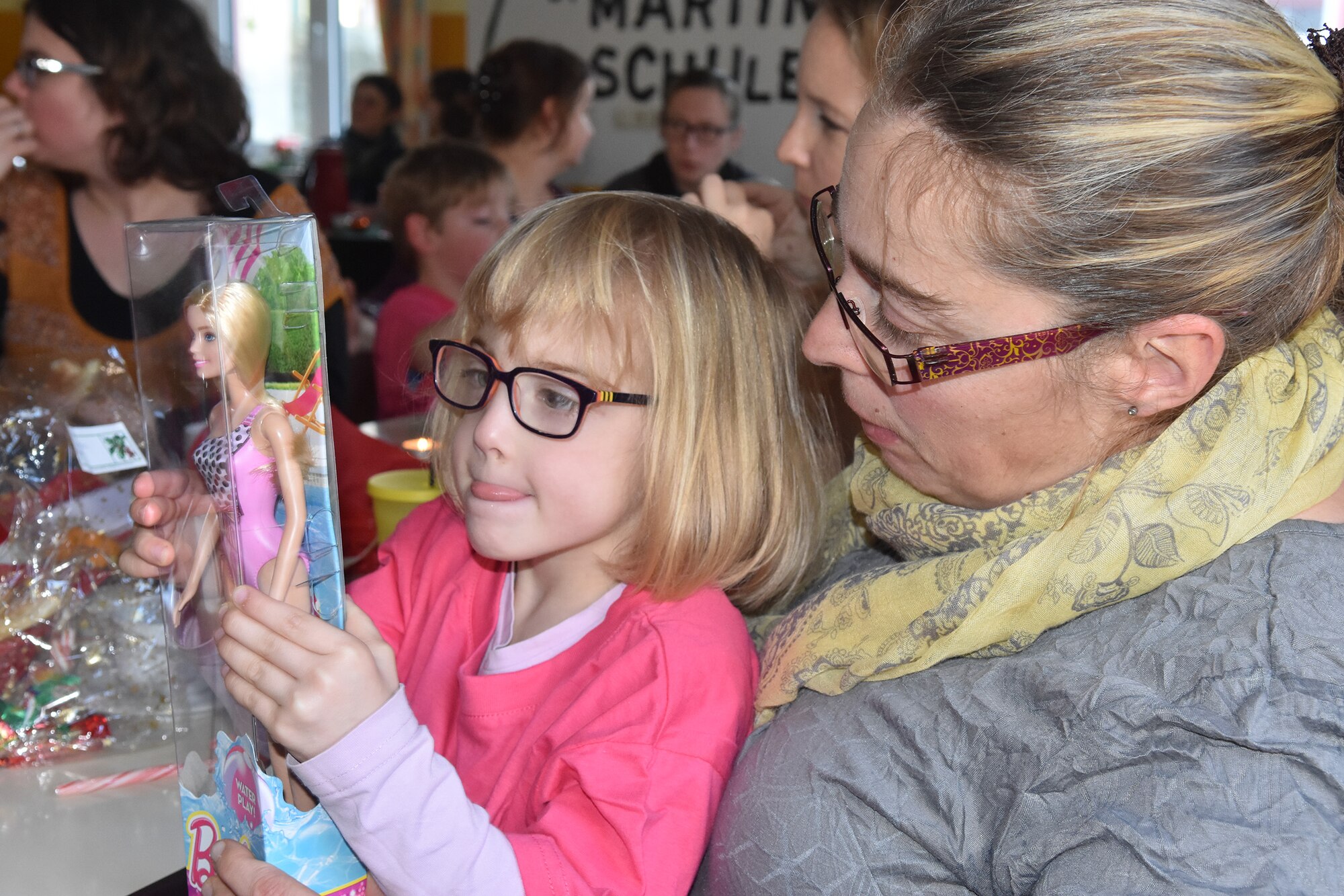 Together with her mother, a girl from the Bitburg Saint Martin school enjoys looking at her new toy, which was just presented to her by a Spangdahlem Air Base Airman during the school’s annual Sankt Nikolaus celebration Dec. 7. The children of Saint Martin school visited Spangdahlem Air Base earlier in the year for Special Children’s Day, and some of the organizers from that event also came to the holiday celebration to help spread cheer among the school children. (U.S. Air Force photo by Iris Reiff/Released)