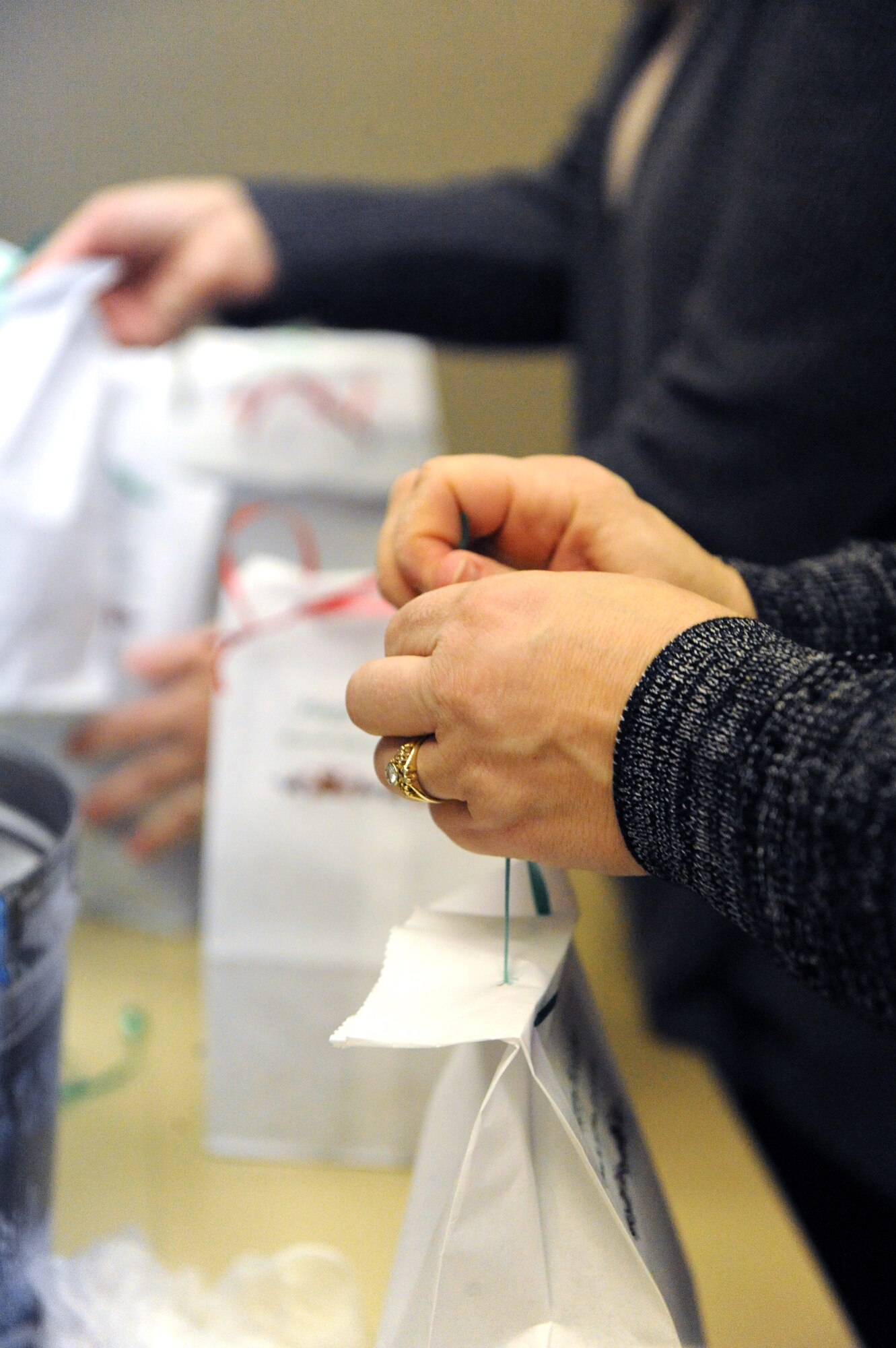 Volunteers tie ribbons on cookie bags during the holiday cookie drive at Whiteman Air Force Base, Mo., Dec. 10, 2015.  Volunteers collected, divided, bagged and distributed more than 600 cookies to unaccompanied and single Airmen living in the dorms. (U.S. Air Force photo by Tech. Sgt. Miguel Lara III)