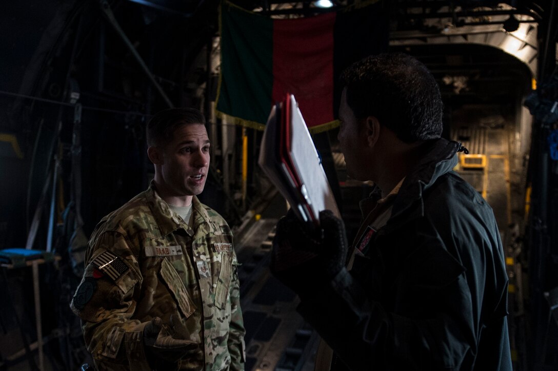 U.S Air Force Tech. Sgt. Nathan Raab instructs an Afghan Air Force loadmaster inside of an Afghan Air Force C-130H Hercules at Hamid Karzai International Airport, Kabul, Afghanistan, Dec. 6, 2015. Raab’s mission is to train, advise, and assist our Afghan partners to develop a professional, capable, and sustainable Air Force. (U.S. Air Force photo by Staff Sgt. Corey Hook/Released)