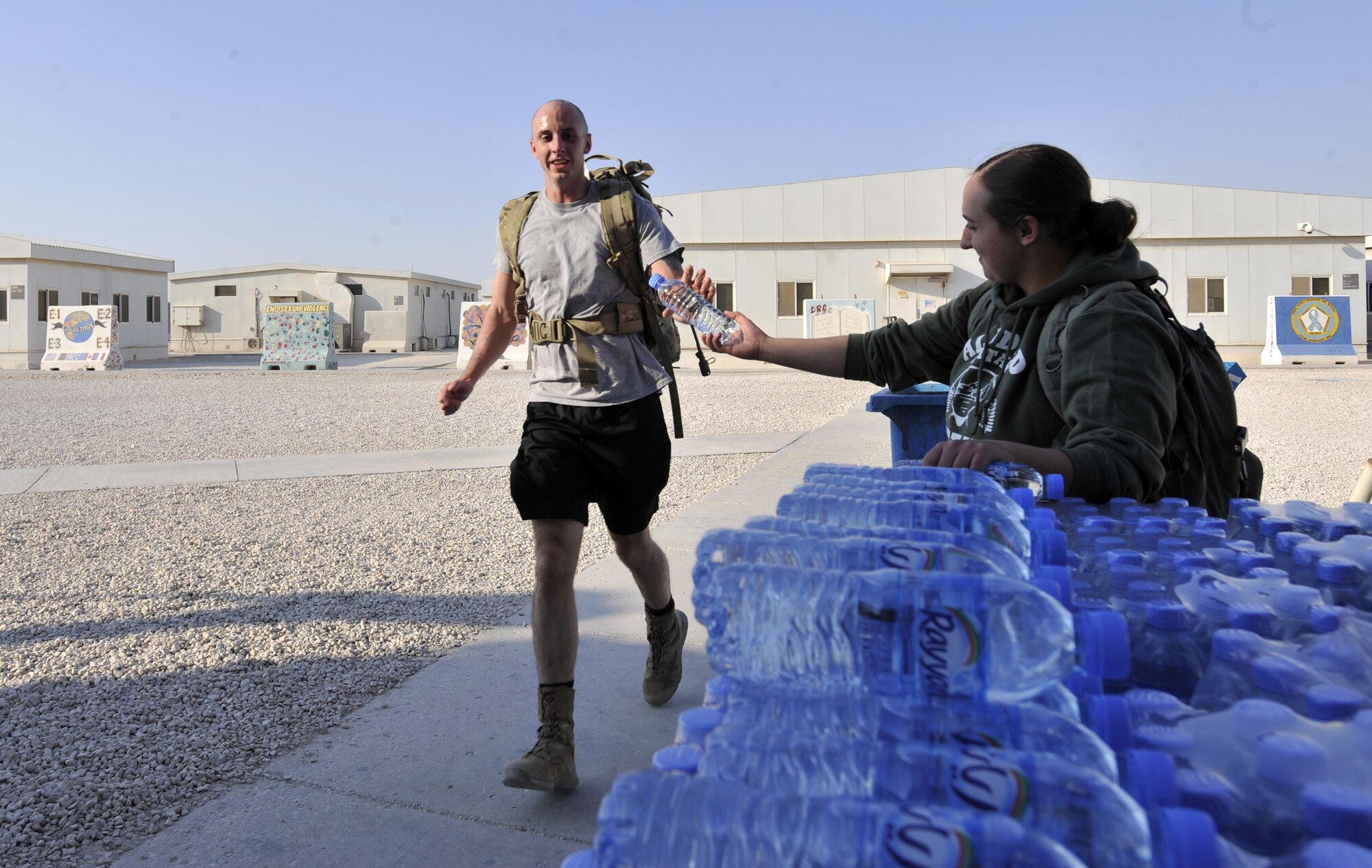 A members of Al Udeid Air Base, Qatar receives a bottle of water as he finishes the Fallen Defenders Ruck to Remember here, Dec. 12, 2015. The 12 kilometer ruck march honors security forces Defenders who have made the ultimate sacrifice in support of operations in Iraq and Afghanistan. (U.S. Air Force photo by Master Sgt. Joshua Strang)