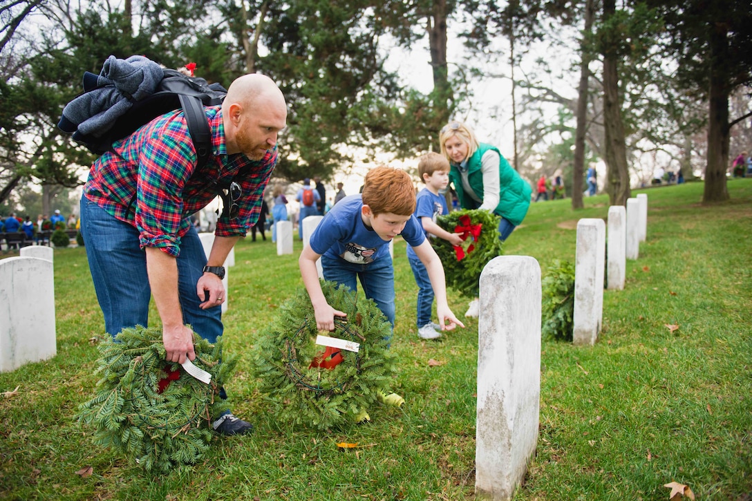 From left, Kevin, Thomas, 8, Ben, 5, and Bethany Roshak place wreaths on headstones in Arlington National Cemetery, in Arlington, Va., Dec. 12, 2015. During the annual Wreaths Across America event, volunteers placed a wreath on every eligible headstone in the cemetery to honor the fallen. U.S. Army photo by Rachel Larue