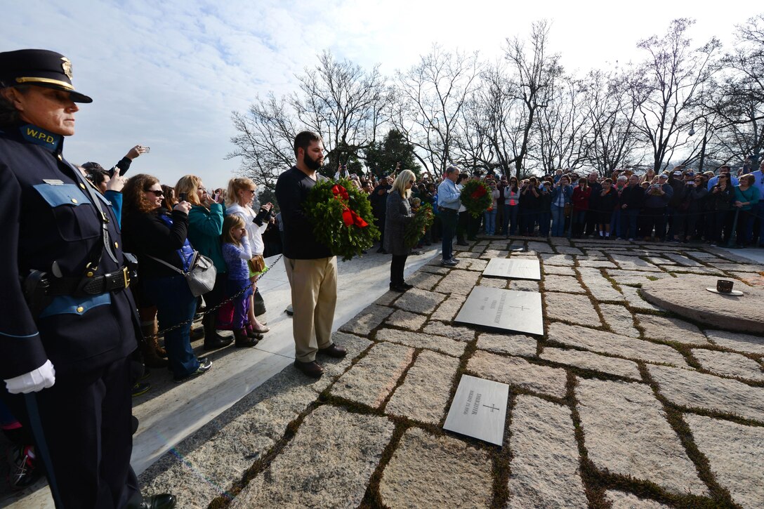 From left to right; Eric, Bessy, Kenneth and Emily Cianchectte prepare to place wreaths at the grave markers of the late president John F. Kennedy, Jacqueline Kennedy and children during the annual Wreaths Across America event at Arlington National Cemetery in Arlington, Va., Dec. 12, 2015. Janine L. Roberts, left, Police Chief, Westbrook, Maine and far right, Kevin Haley, a police officer from Portland, Maine, stand in observance. DoD photo by Sebastian Sciotti Jr.
