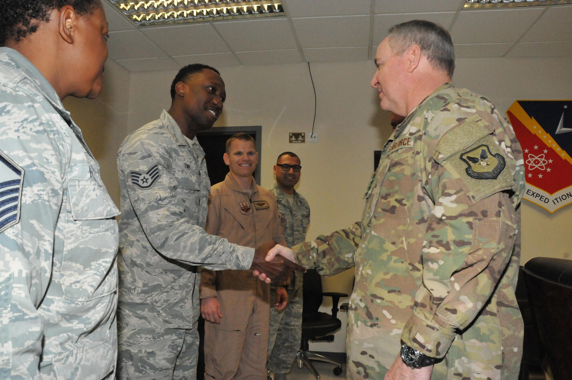 Gen. Mark Welsh III, Chief of Staff of the Air Force, coins Staff Sgt. Quentin Toney, 379th Maintenance Group Maintenance Operations Flight, Dec. 11 at Al Udeid Air Base, Qatar. Master Sgt. Rosalynn Howard, Toney’s supervisor, told Welsh how Toney manages the largest aircraft fleet in the U.S. Central Command area of responsibility and coordinates with 24 home station units to move over 300 hundred aircraft rotating in and out of AUAB. (U.S. Air Force photo by Tech. Sgt. Terrica Y. Jones)