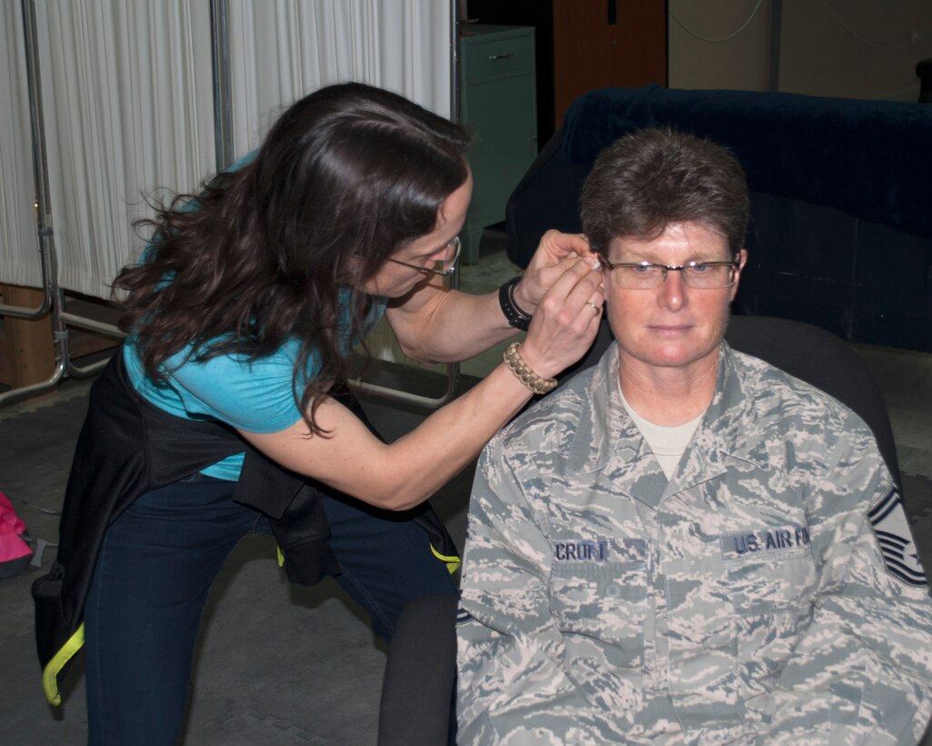 Air Force Maj. Sarah Ayers, left, 386th Expeditionary Medical Squadron physician, applies acupuncture therapy to Senior Master Sgt. Julie Croft, 386th Expeditionary Communications Squadron plans and programs flight chief, during a base Health Fair at an undisclosed location in Southwest Asia Dec. 12, 2015.  The 386th Expeditionary Medical Group hosts the fair twice a year in combination with the 386 AEW Sexual Assault Response Coordinator, Chaplain and Force Support Squadron, focusing on the three pillars of health and wellness - Mental, Physical, and Spiritual.  (U.S. Air Force photo by Maj. John Stamm)