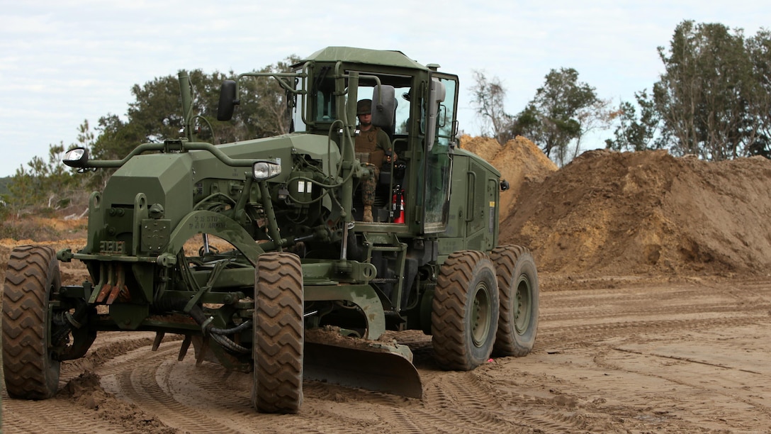 A Marine operates a motor grader to level the ground for a vertical take-off and landing aircraft pad at Marine Corps Auxiliary Landing Field Bogue, N.C., Dec. 9, 2015. Marines with Marine Wing Support Squadron 271’s Engineer Company participated in a cantonment and capabilities field exercise to practice and improve their knowledge of their jobs while in a deployed environment. The weeklong exercise featured events such as airfield damage repair, water purification, medium and heavy lifting missions, with the construction of an expedient road for a vertical take-off and landing aircraft pad. 