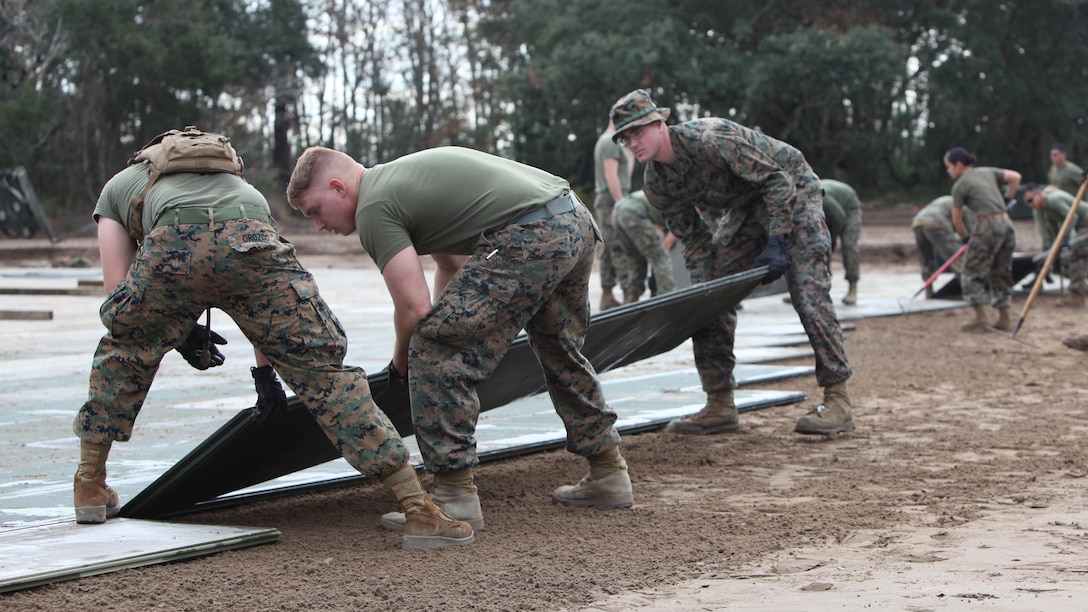 Marines with Marine Support Squadron 271 assemble a vertical take-off and landing aircraft pad at Marine Corps Auxiliary Landing Field Bogue, N.C., Dec. 9, 2015. Marines with Marine Wing Support Squadron 271’s Engineer Company participated in a cantonment and capabilities field exercise to practice and improve their knowledge of their jobs while in a deployed environment. The weeklong exercise featured events such as airfield damage repair, water purification, medium and heavy lifting missions, with the construction of an expedient road for a vertical take-off and landing aircraft pad.