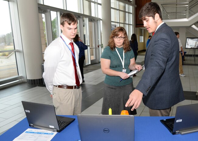 Betina Johsnon, U.S. Army Engineering and Support Center, Huntsville Ordnance and Explosives Design Center chief, speaks to Sebastian Stewart, left, and Liam Bair, Hartselle High School, Hartselle, Alabama, about their conceptual payload during the InSPIRESS event at UA Huntsville, Dec. 11. 